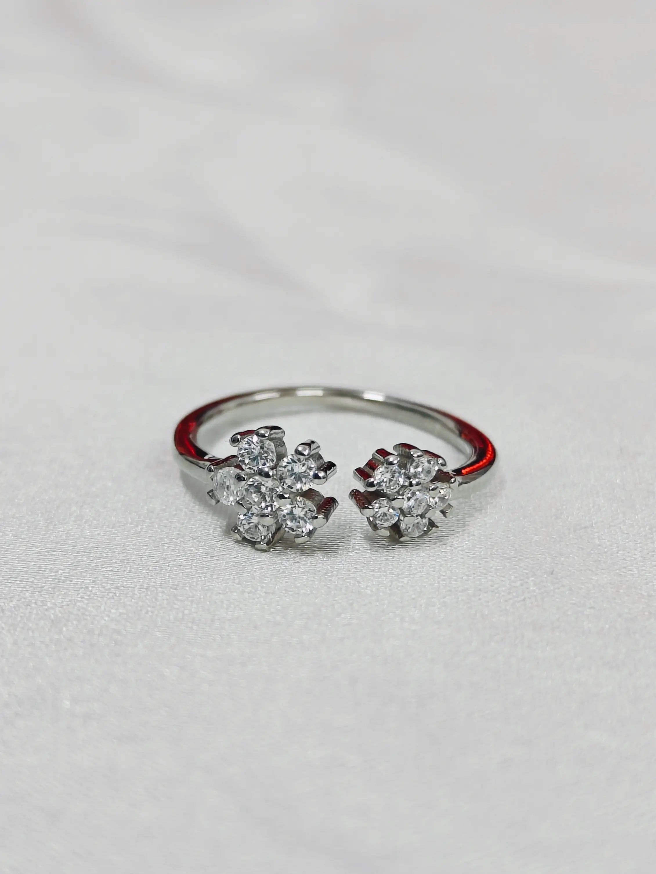 Pair of silver earrings with floral designs on a light gray background