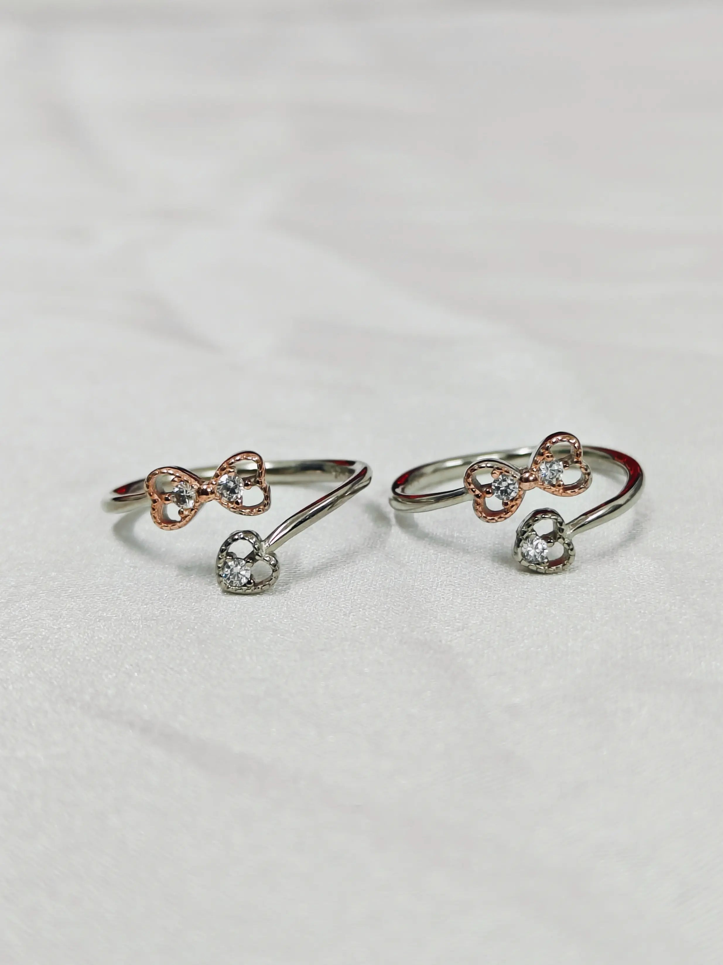 Two delicate rings with bow designs on a light gray background