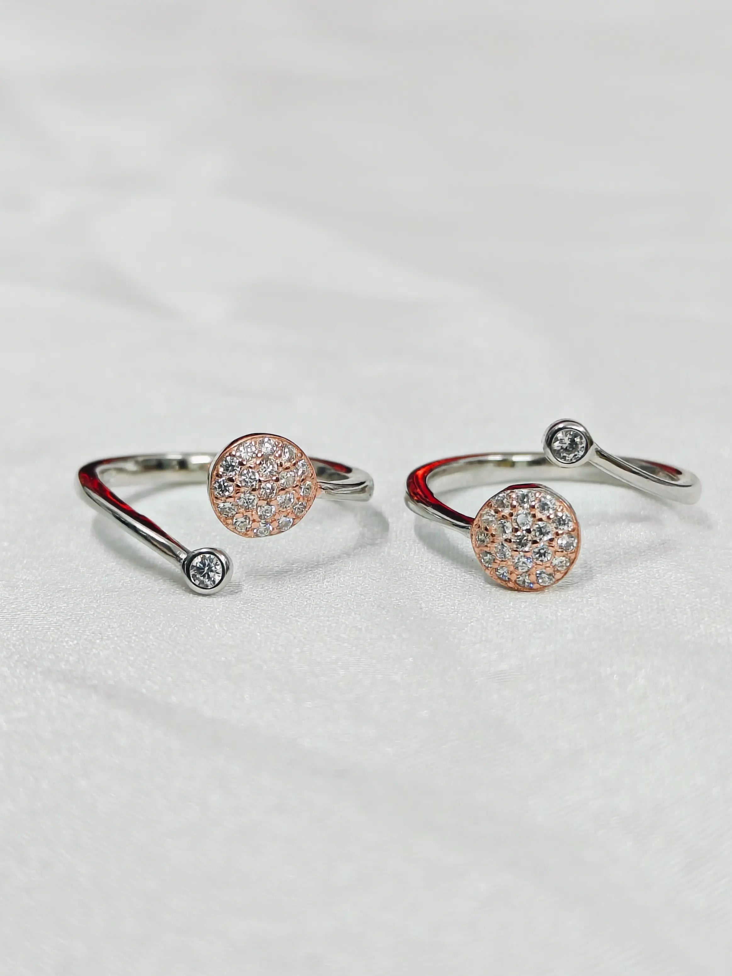 Pair of silver open rings with round gemstones on a light gray background