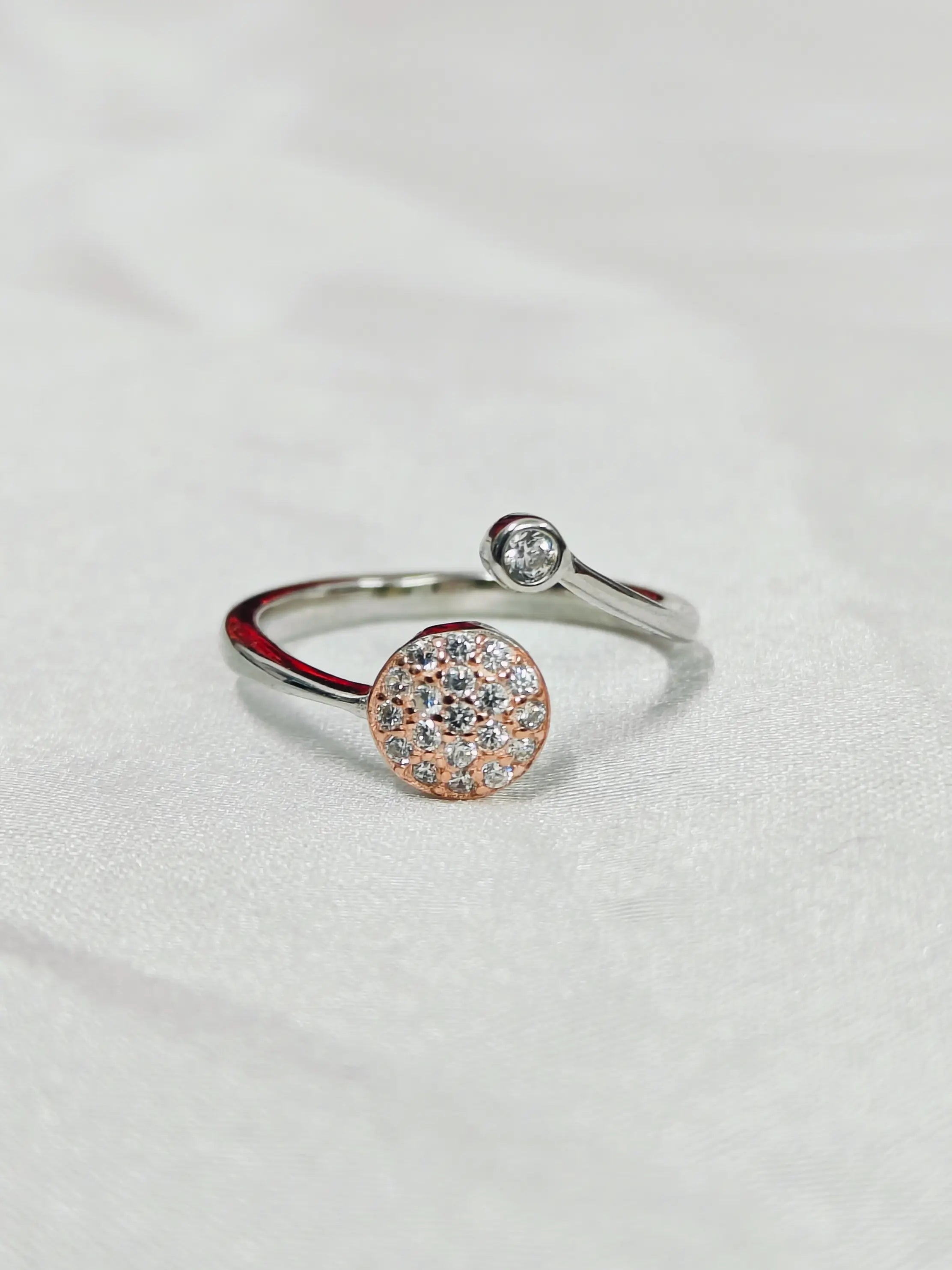 Silver ring with a round, multicolored gemstone on a light gray background