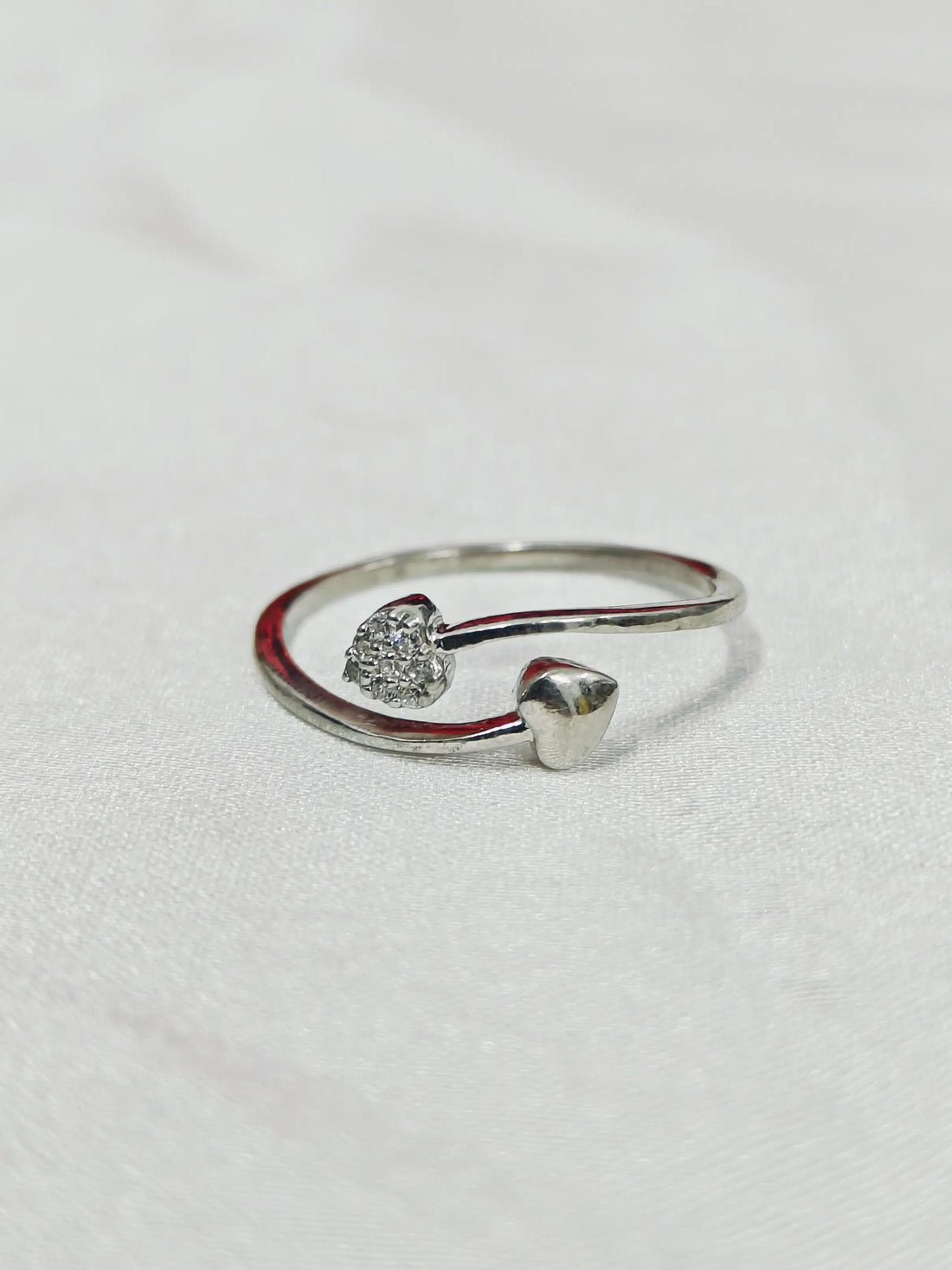 Silver open ring with heart-shaped stones on a light gray background