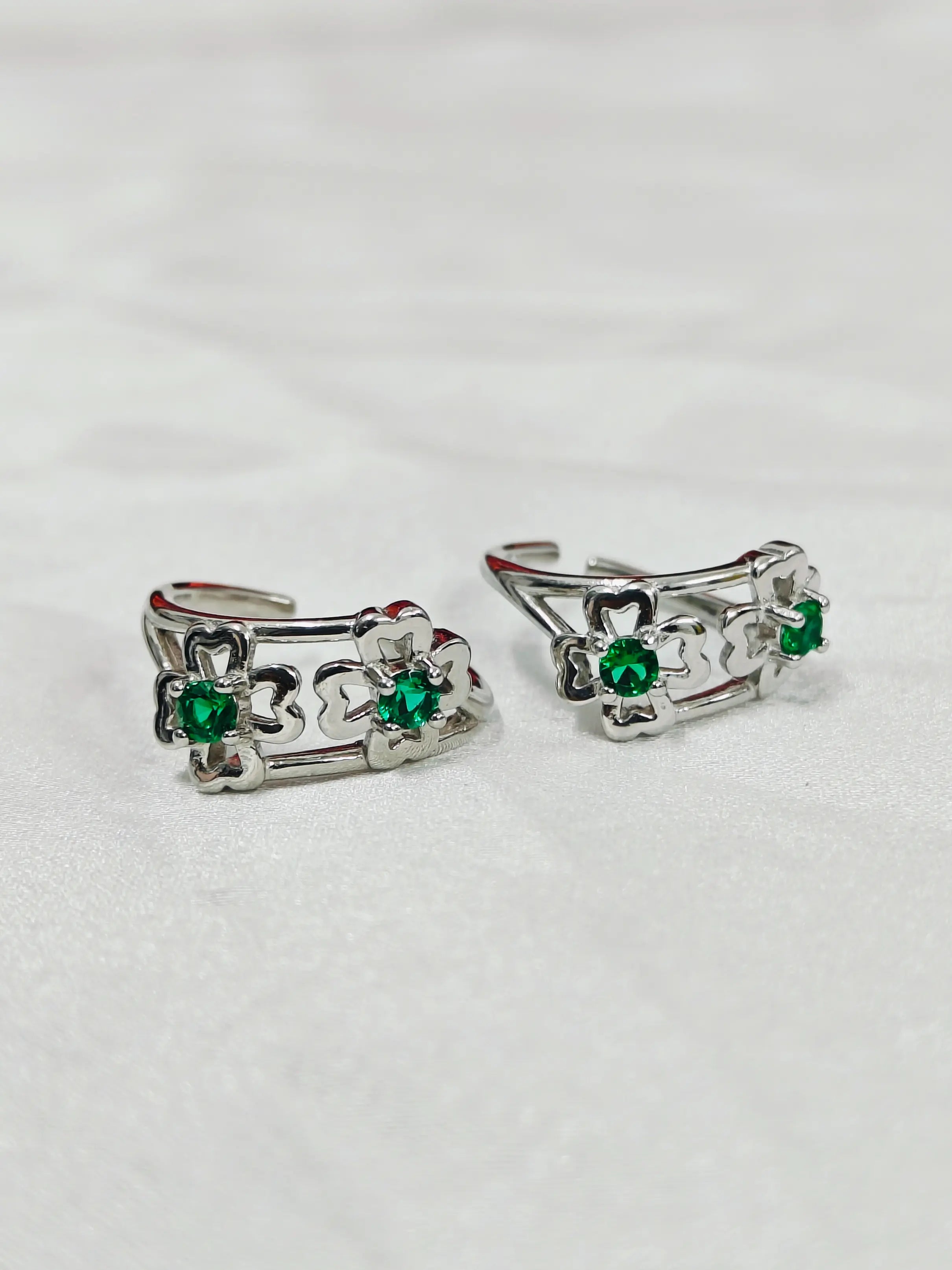 Pair of silver earrings with green gemstones on a white background