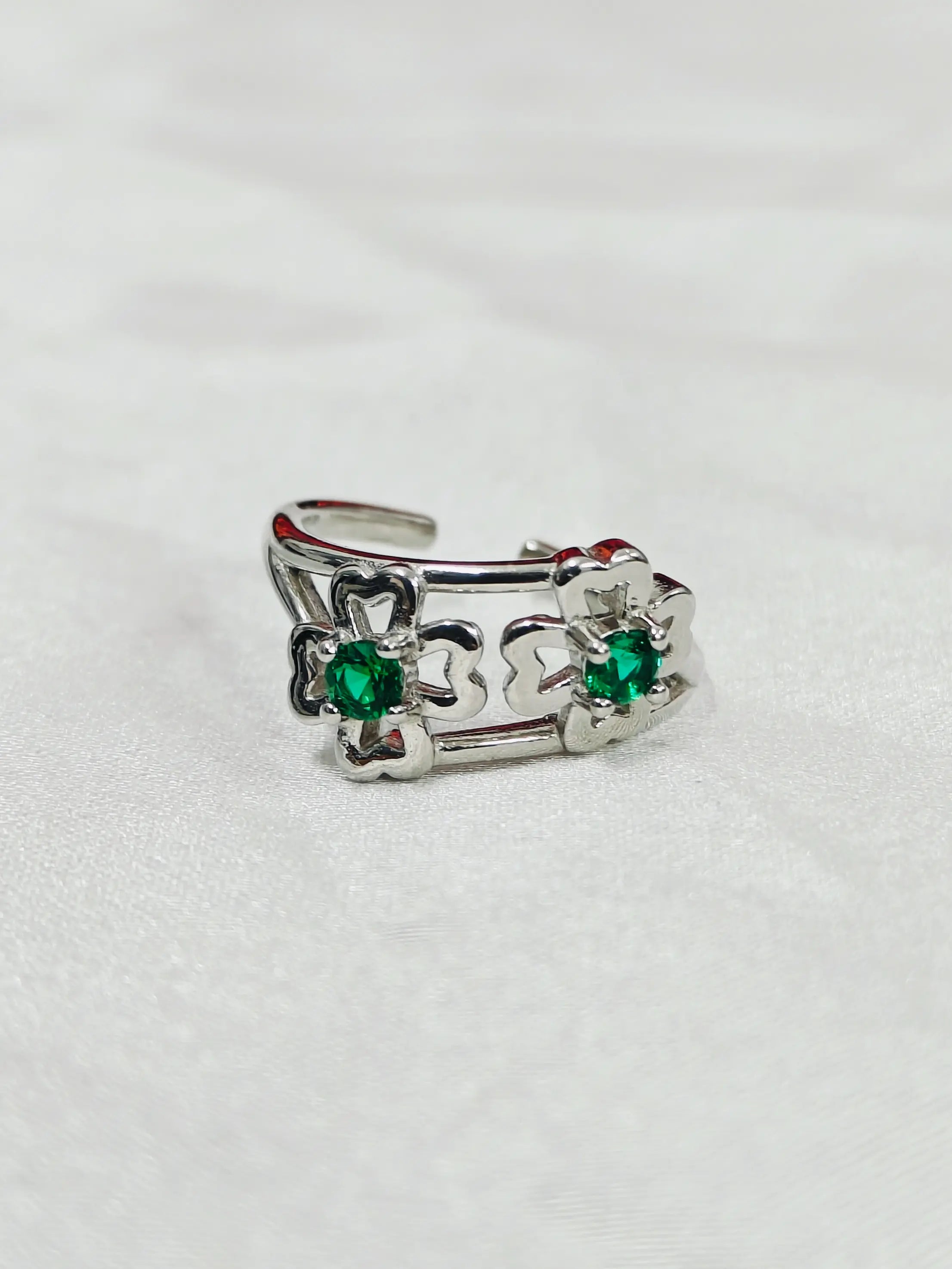 Silver ring with green gemstones on a white background