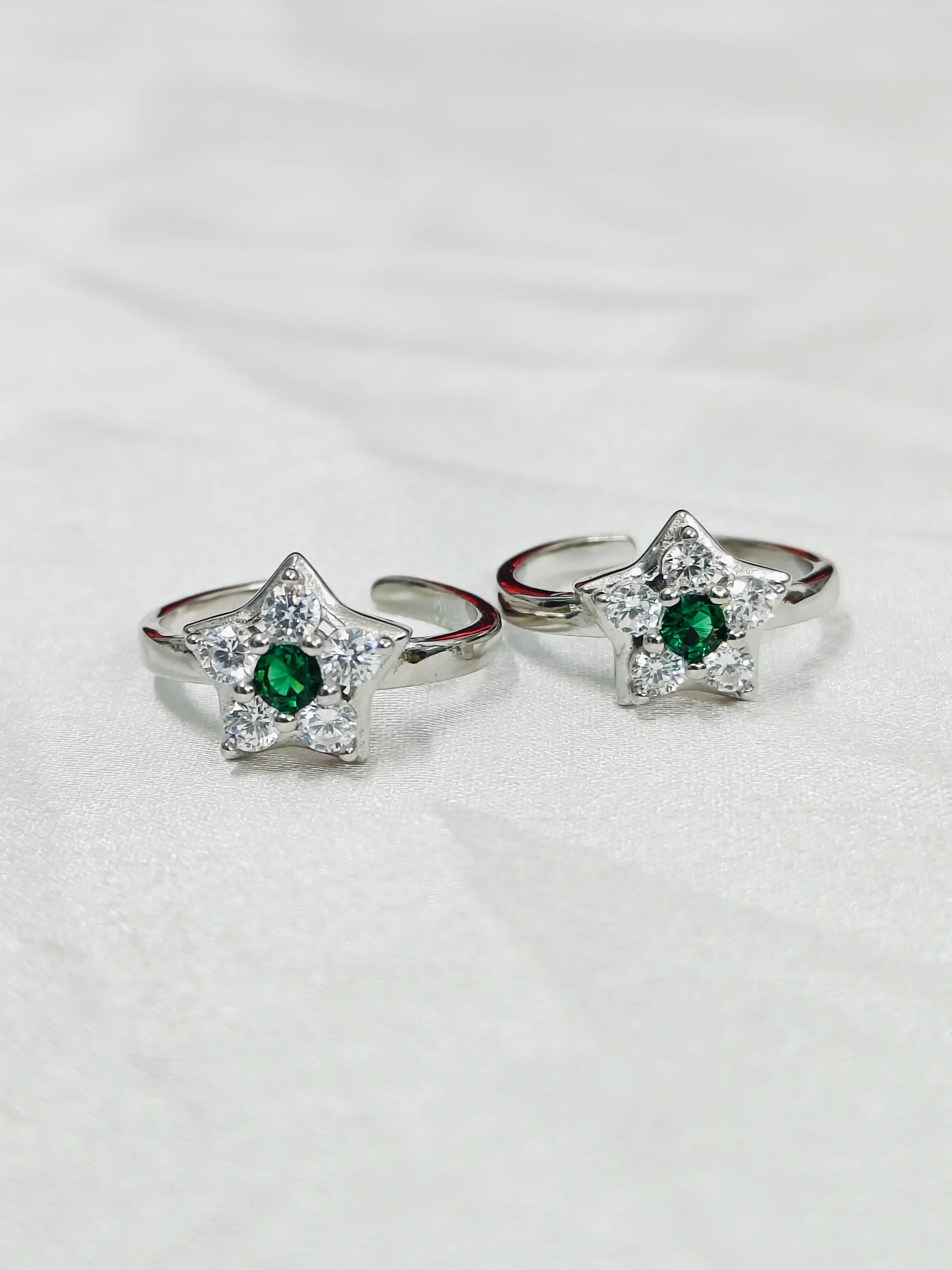 Star-shaped silver rings with green gemstones on a white background