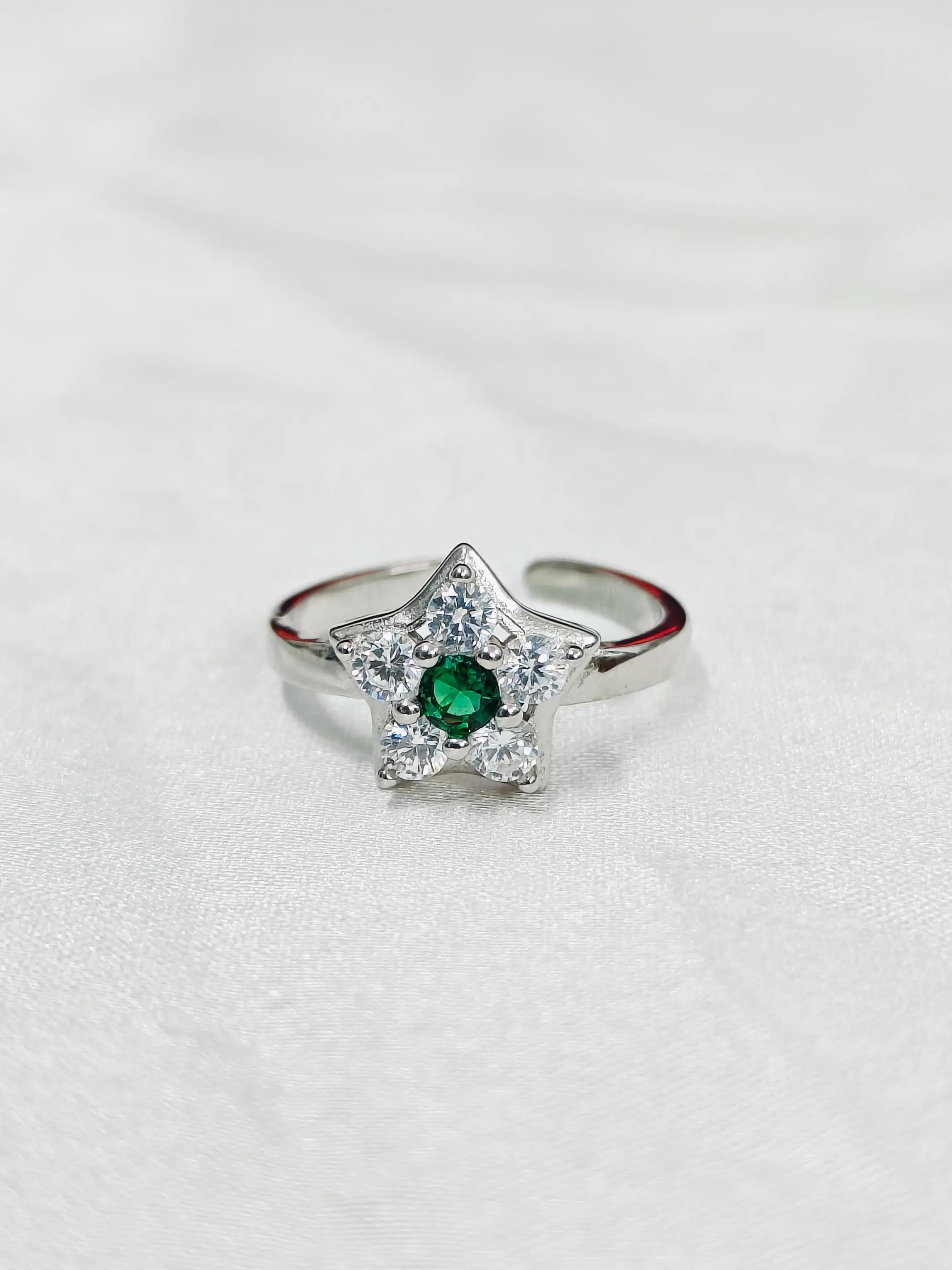 Star-shaped silver ring with a green gemstone on a white background