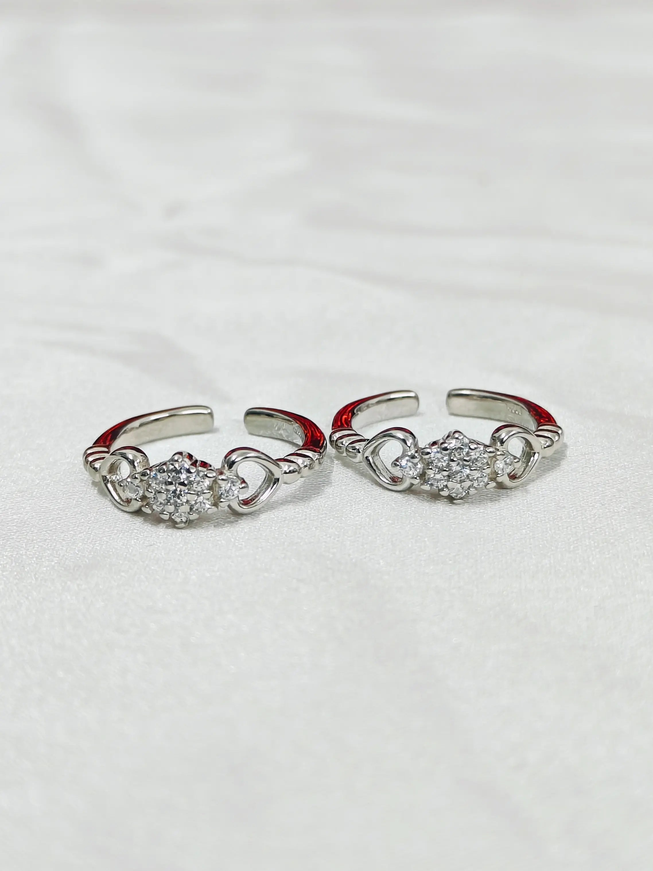 Pair of silver open rings with gemstones on a light gray background