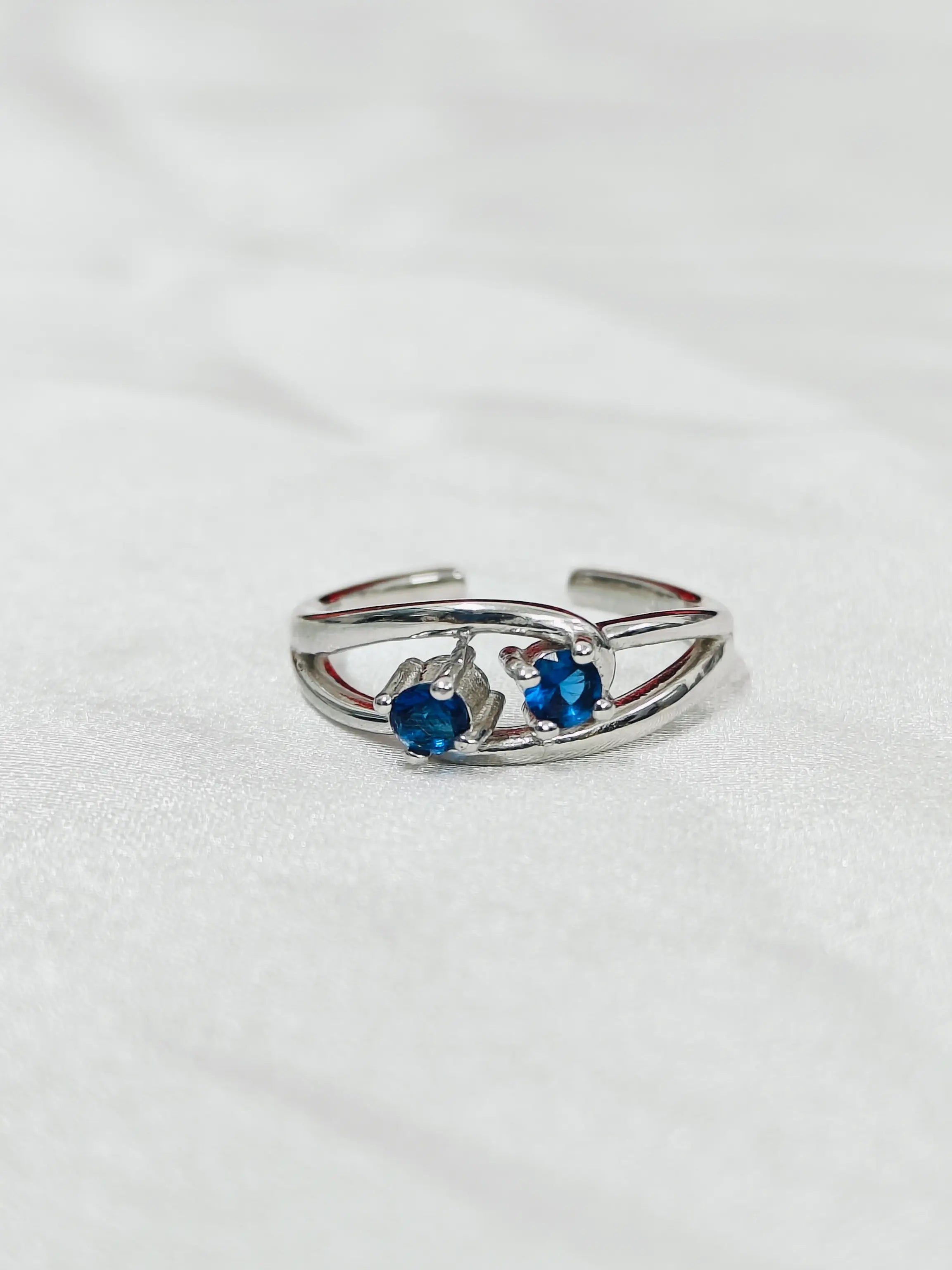 Silver ring with blue gemstones on a white background