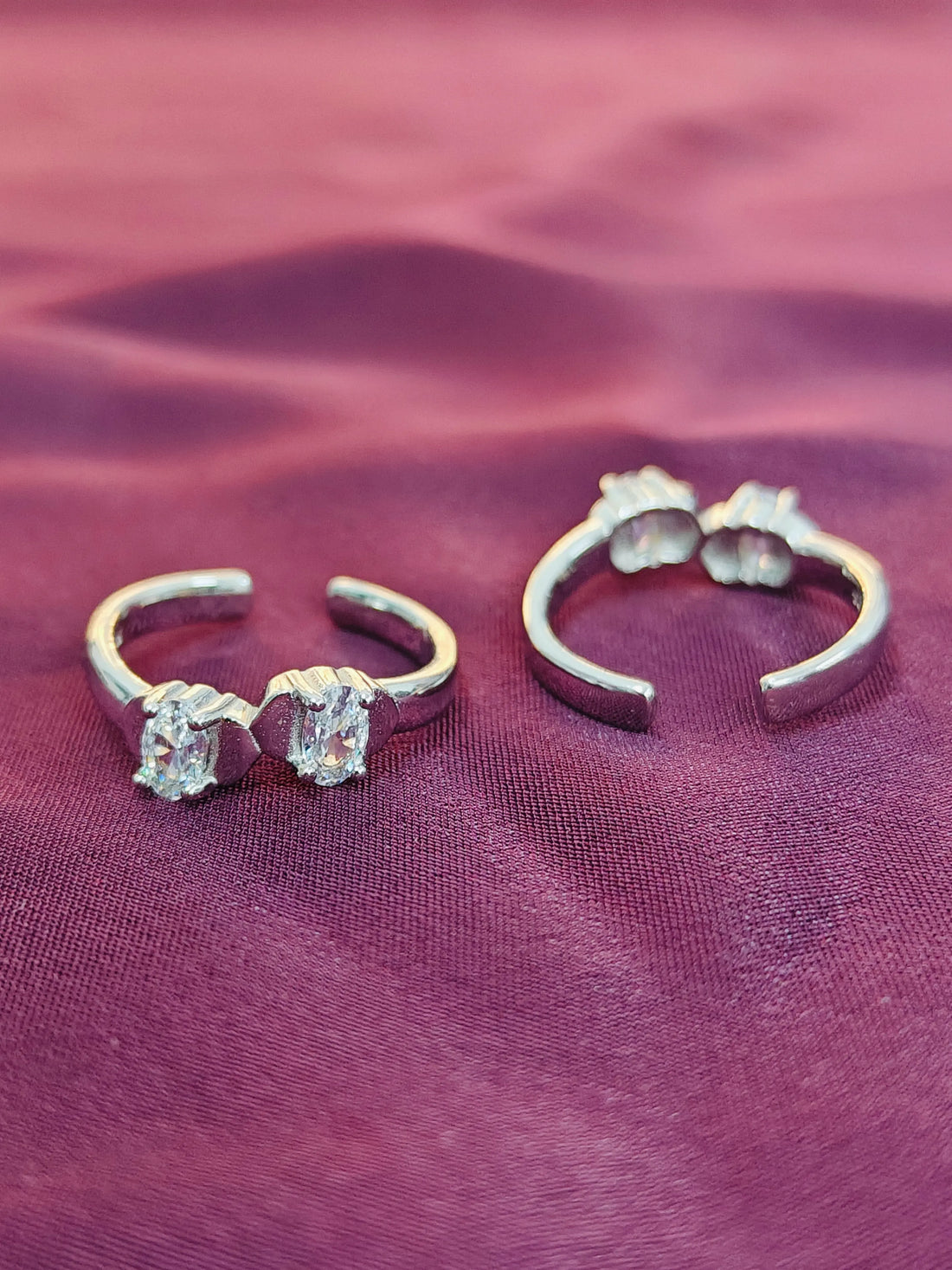 Pair of silver hoop earrings with gemstones on a purple fabric background