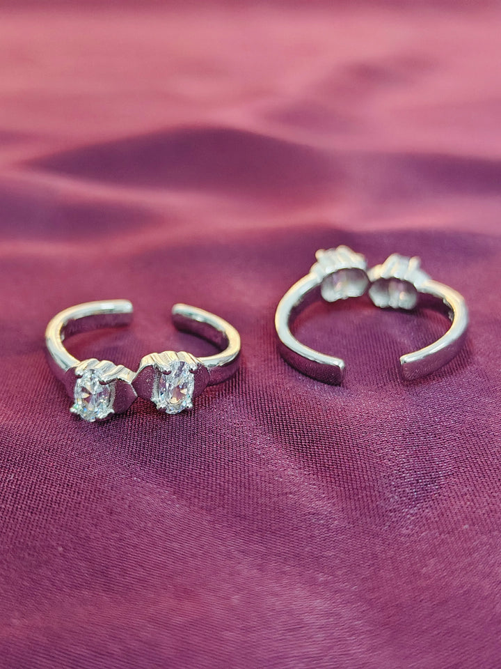 Pair of silver hoop earrings with gemstones on a purple fabric background