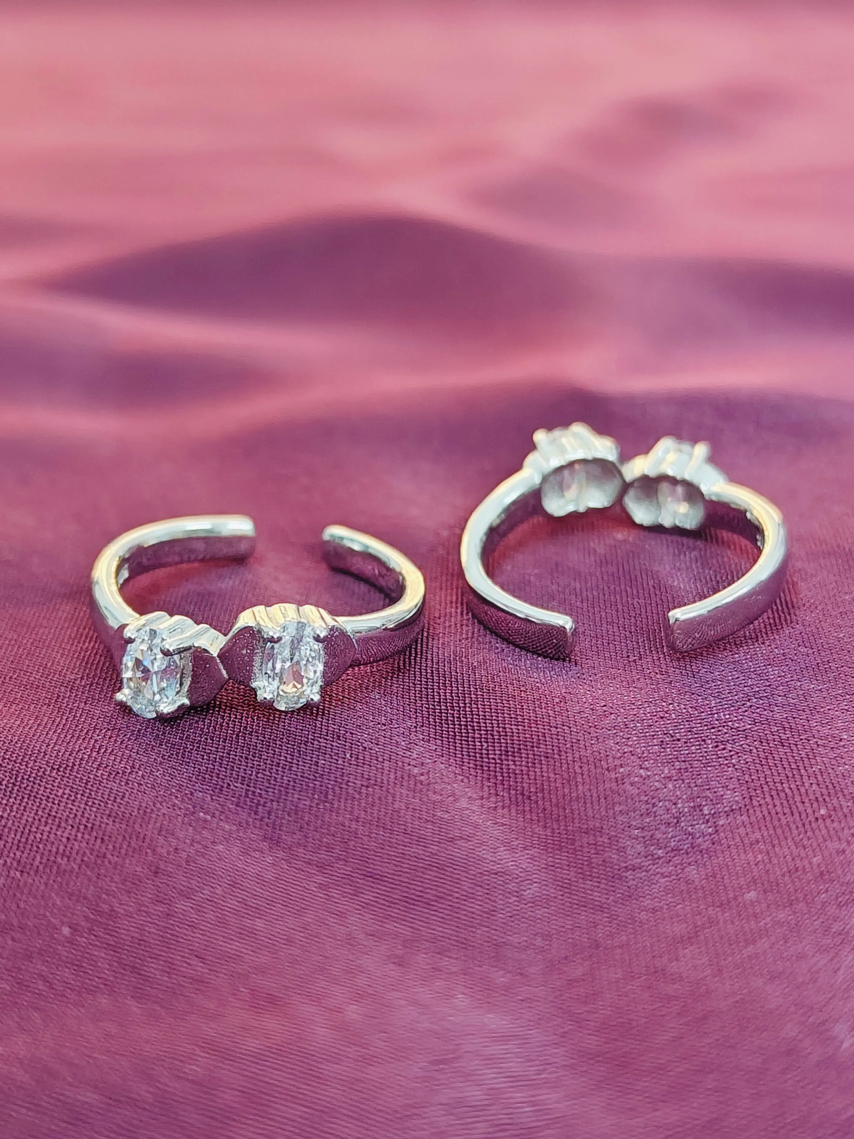 Pair of silver hoop earrings with gemstones on a purple fabric background