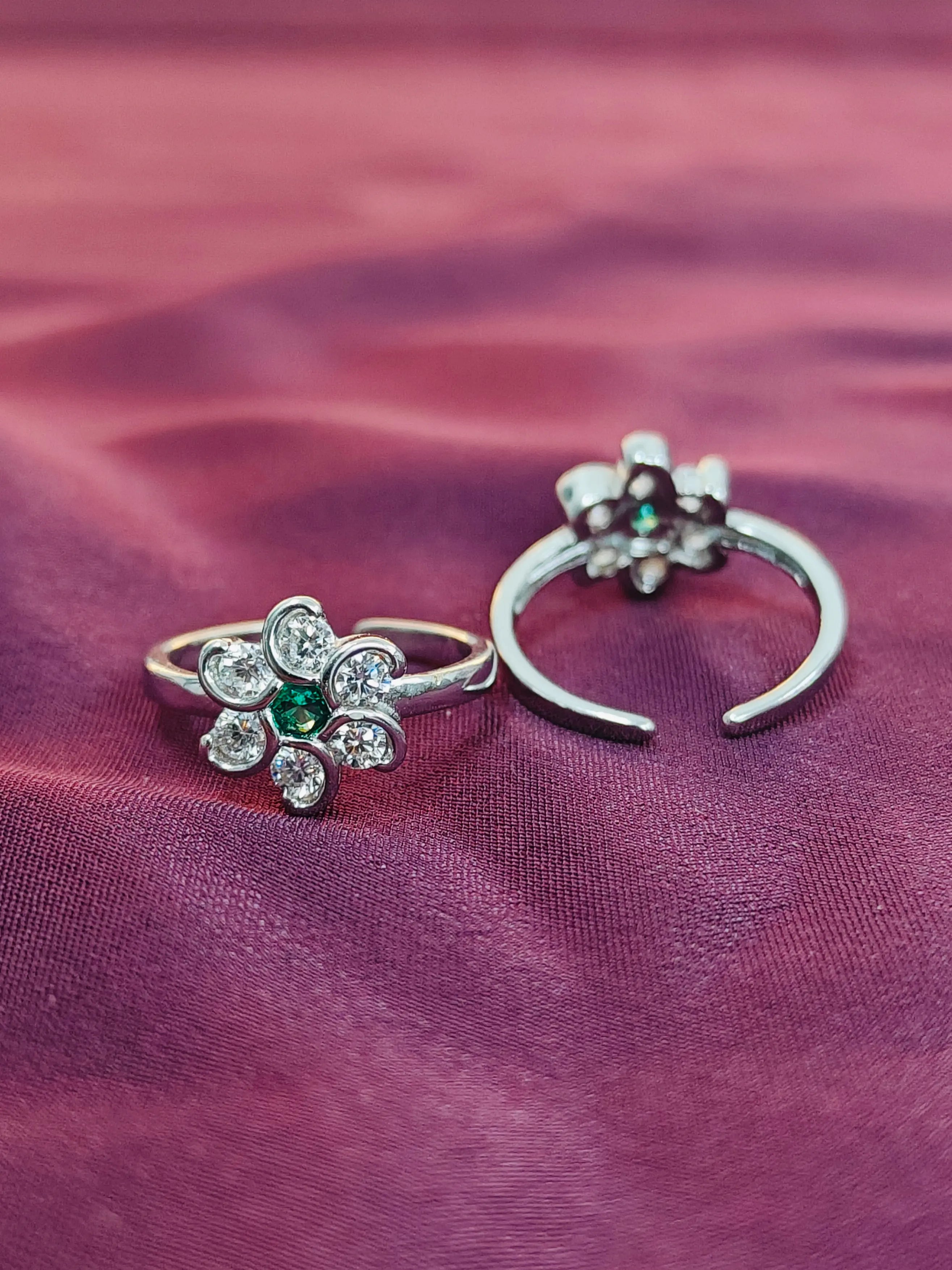 Two silver rings with floral designs on a purple fabric background