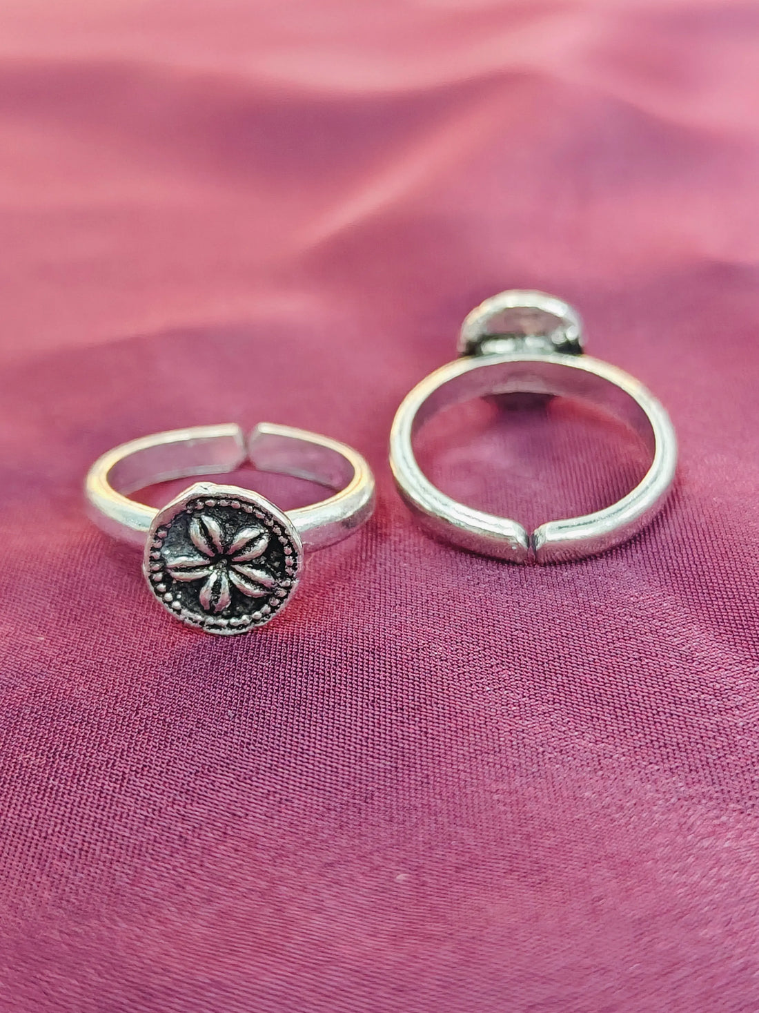 Two silver rings on a pink fabric background