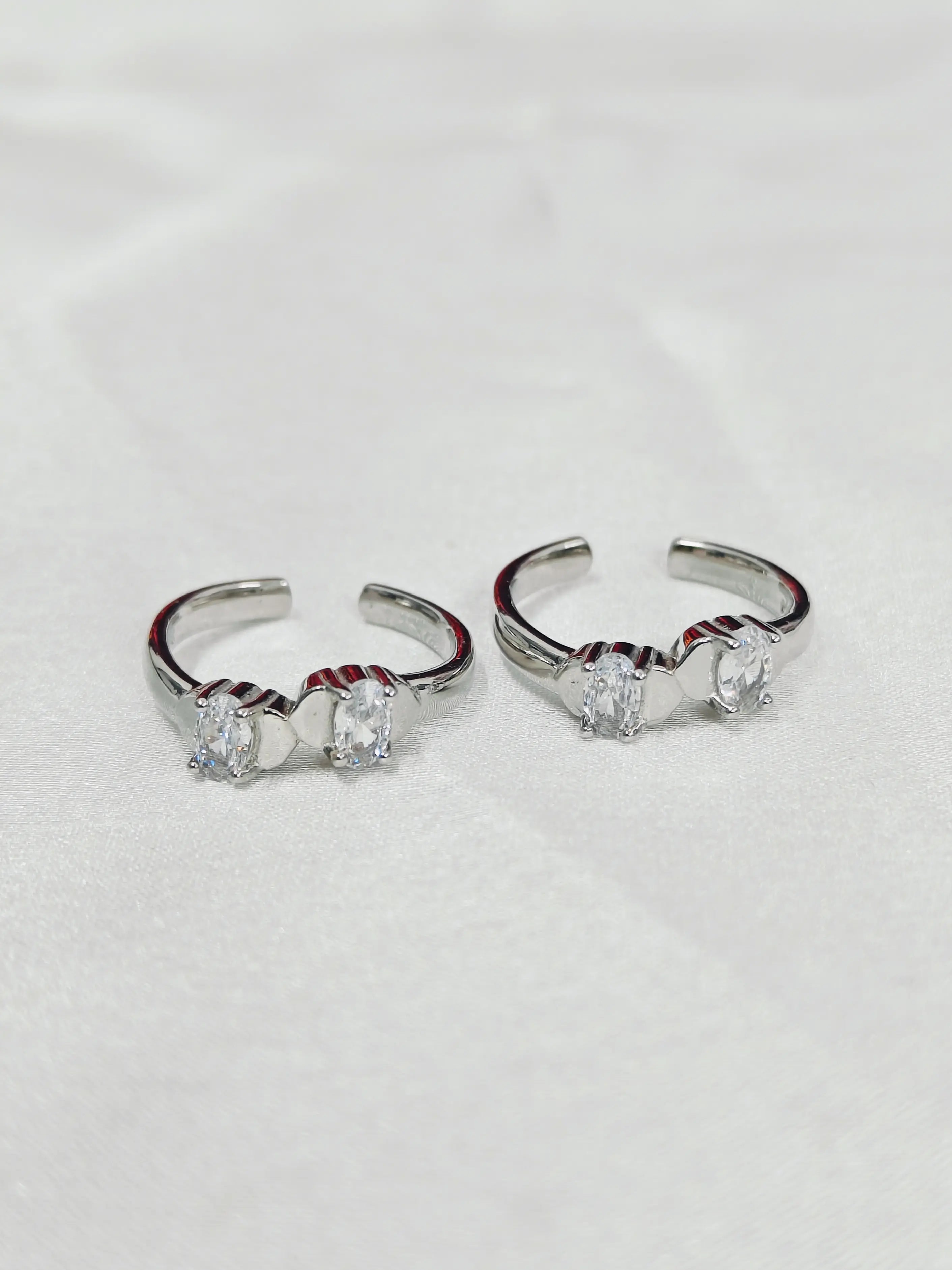 Pair of silver hoop earrings with clear gemstones on a light gray background