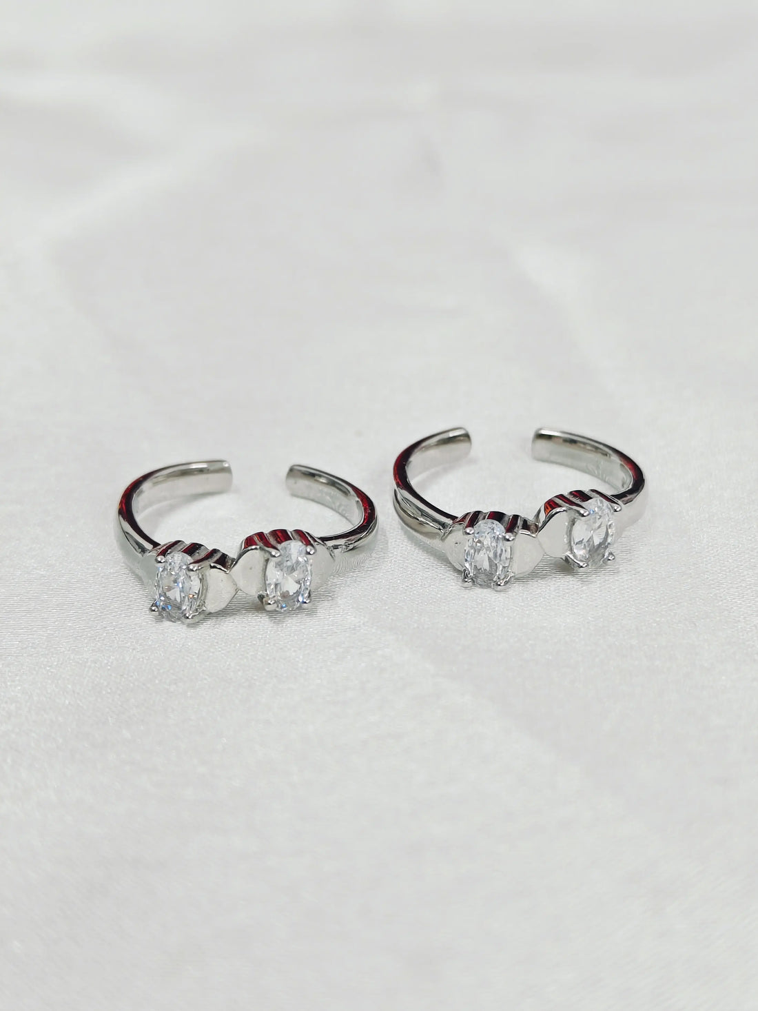 Pair of silver hoop earrings with clear gemstones on a light gray background