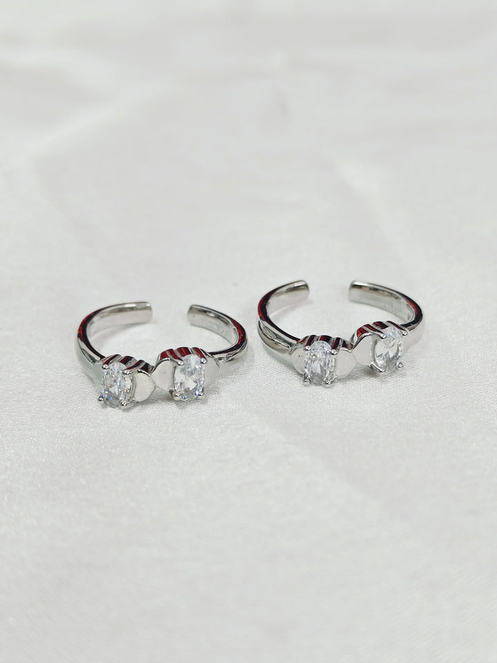 Pair of silver hoop earrings with clear gemstones on a light gray background