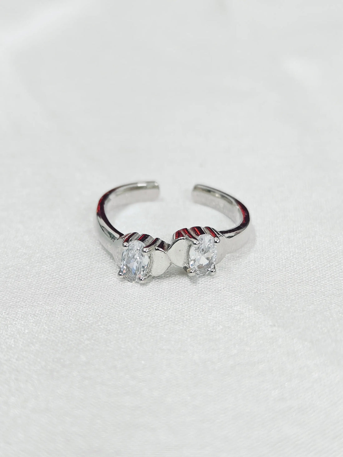 Silver ring with two clear gemstones on a light gray background