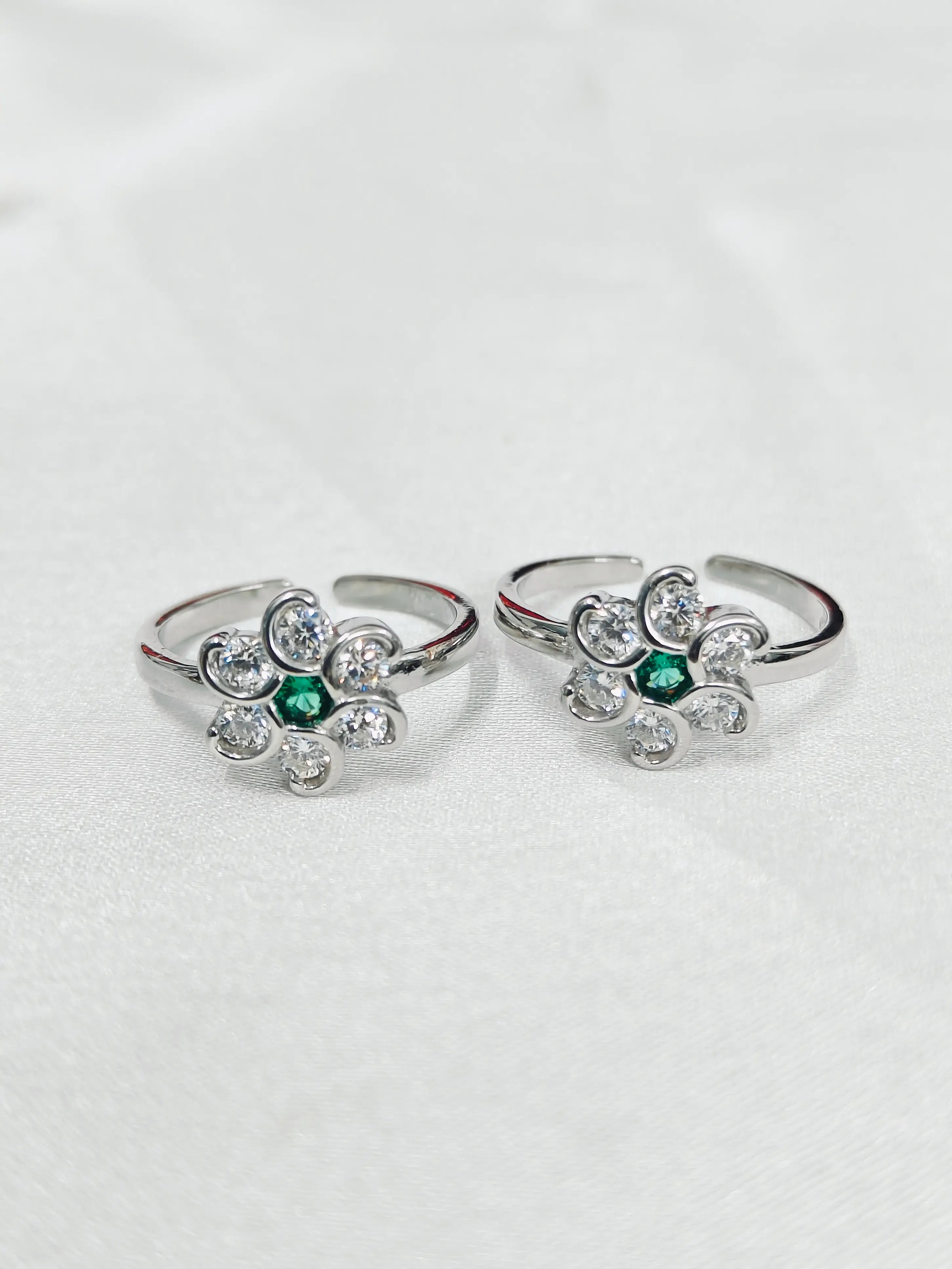 Two silver rings with emerald green stones on a white background