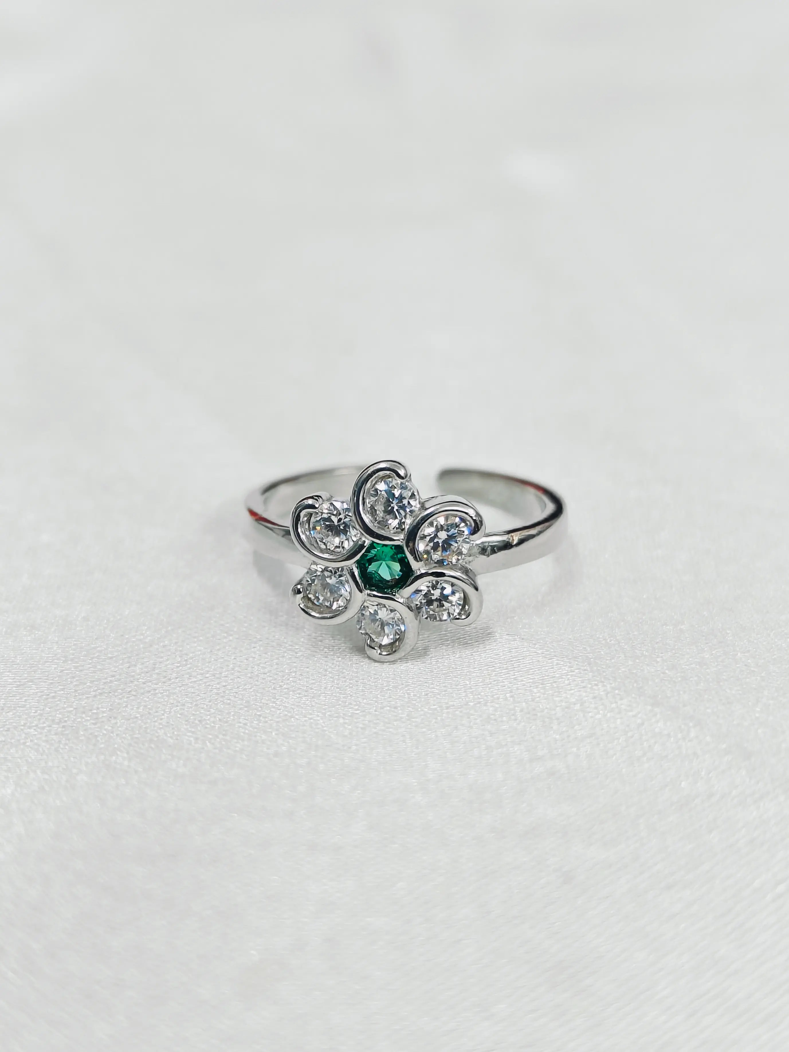 Silver ring with a green gemstone on a white background