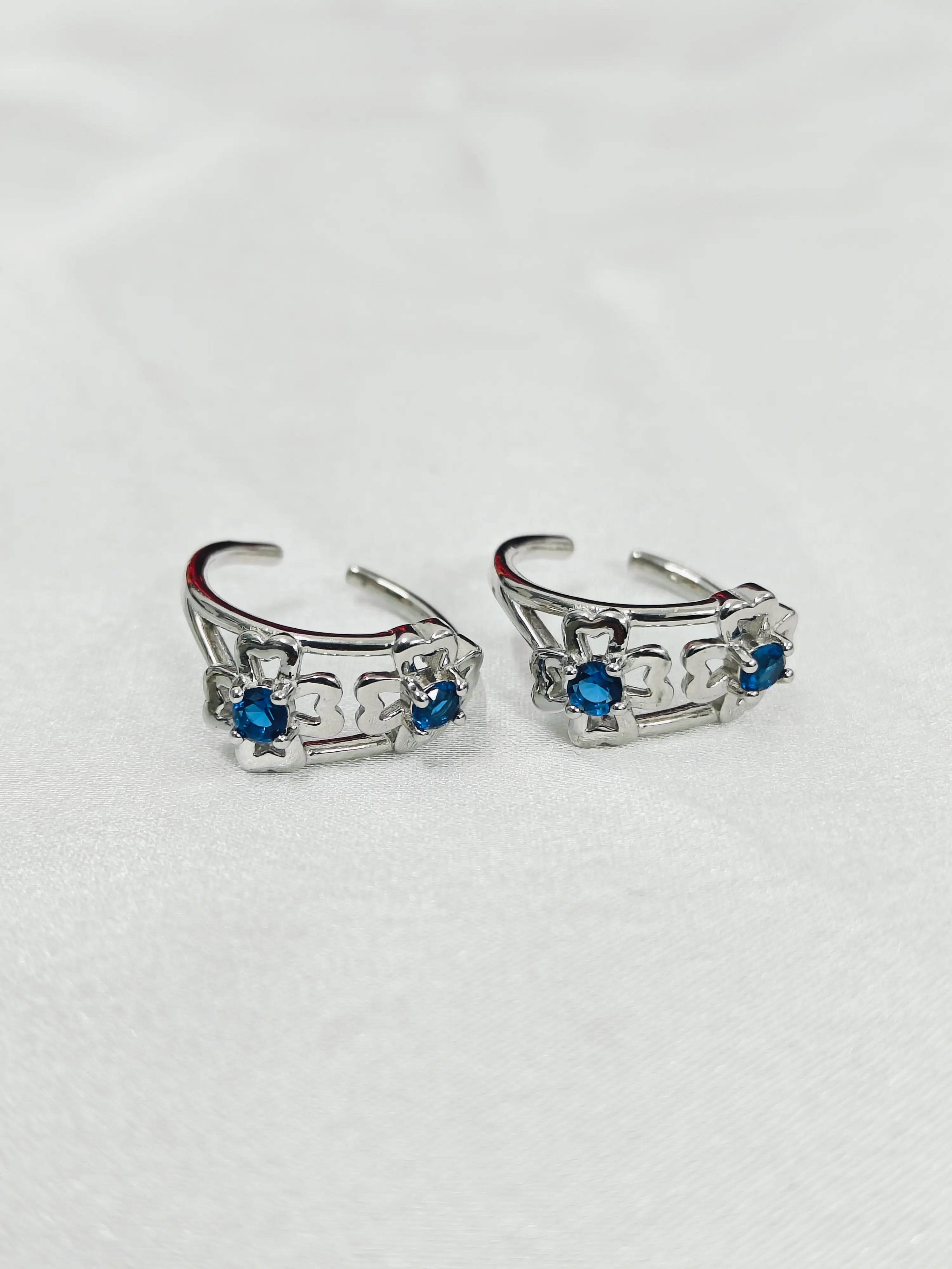 Pair of silver hoop earrings with blue gemstones on a white background