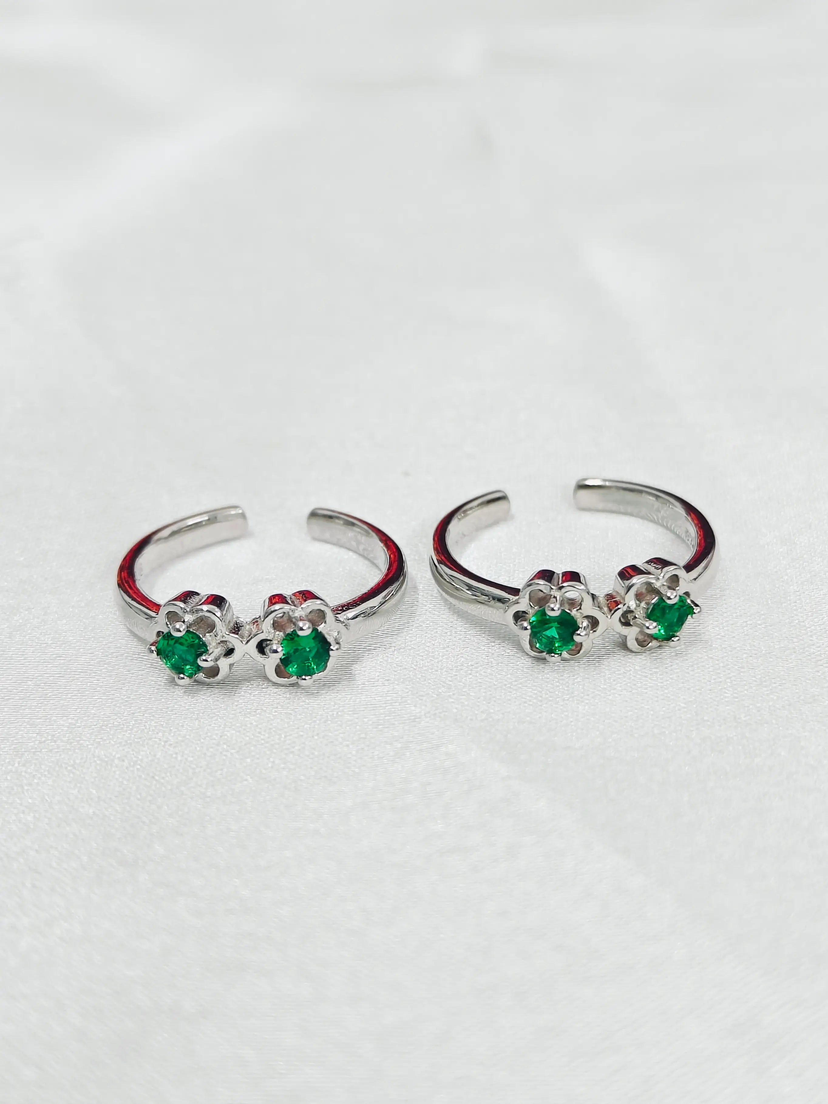 Silver hoop earrings with green gemstones on a white background