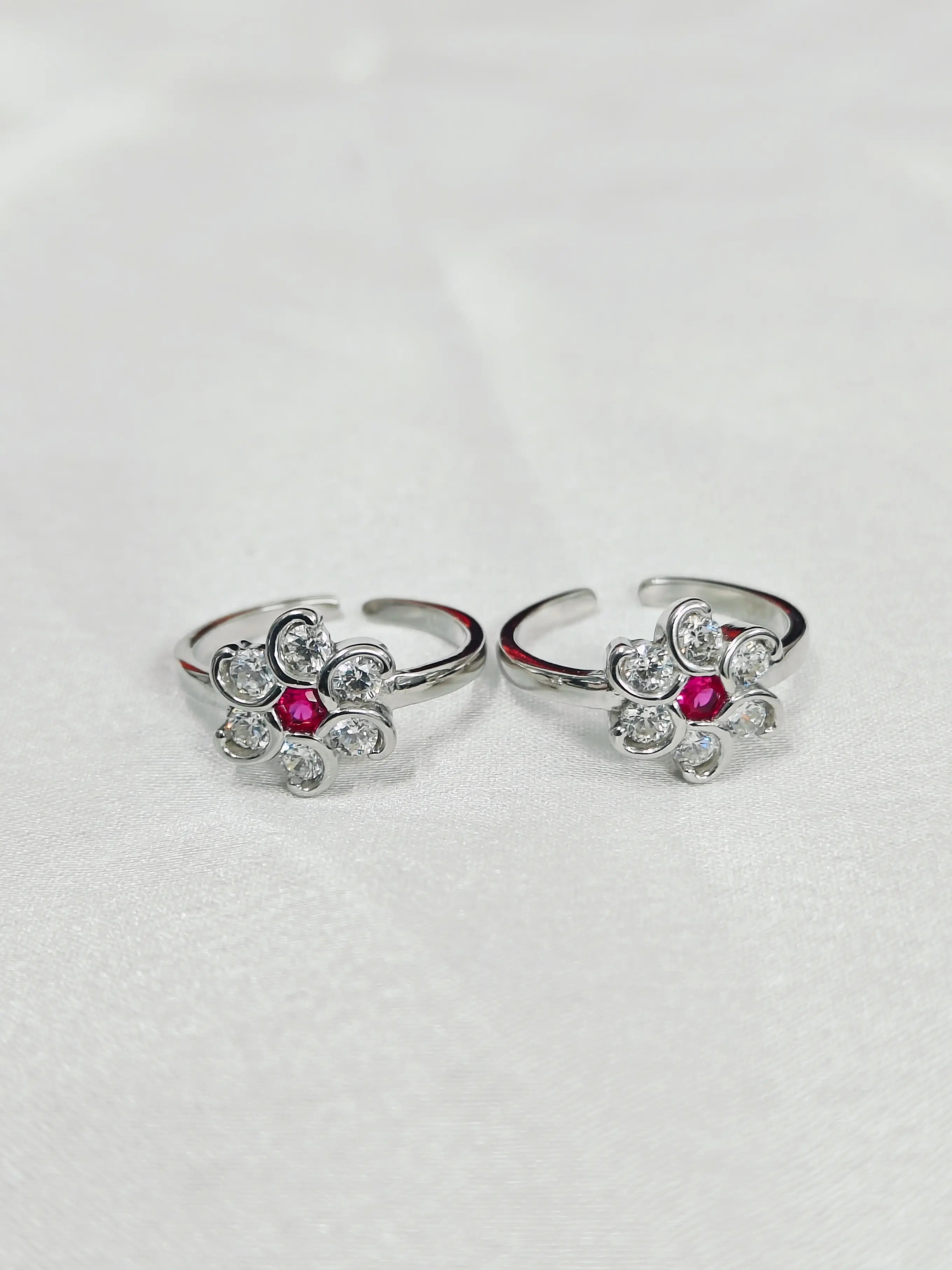 Pair of silver rings with red gemstones on a light gray background