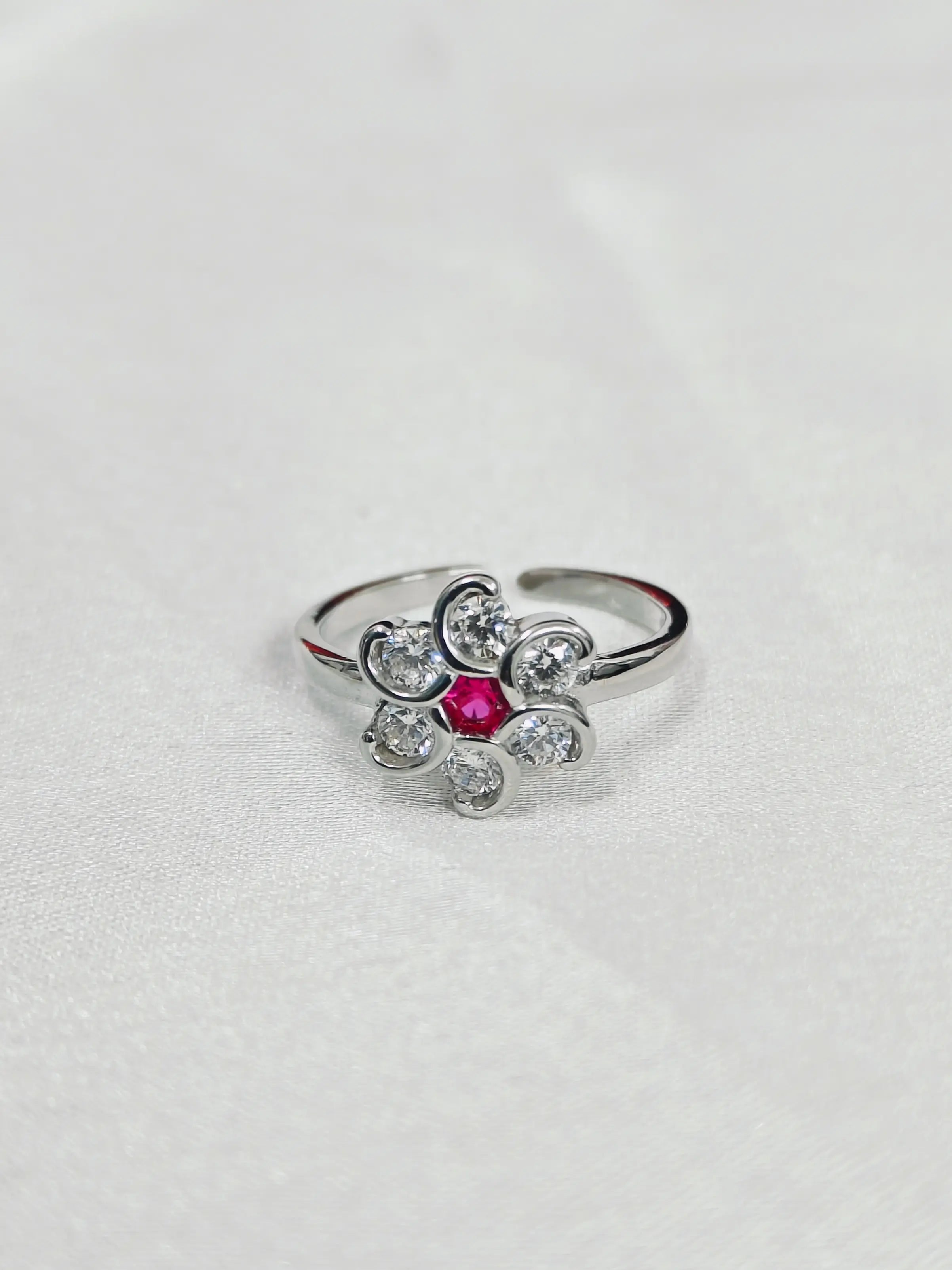 Silver ring with a pink gemstone on a light gray background