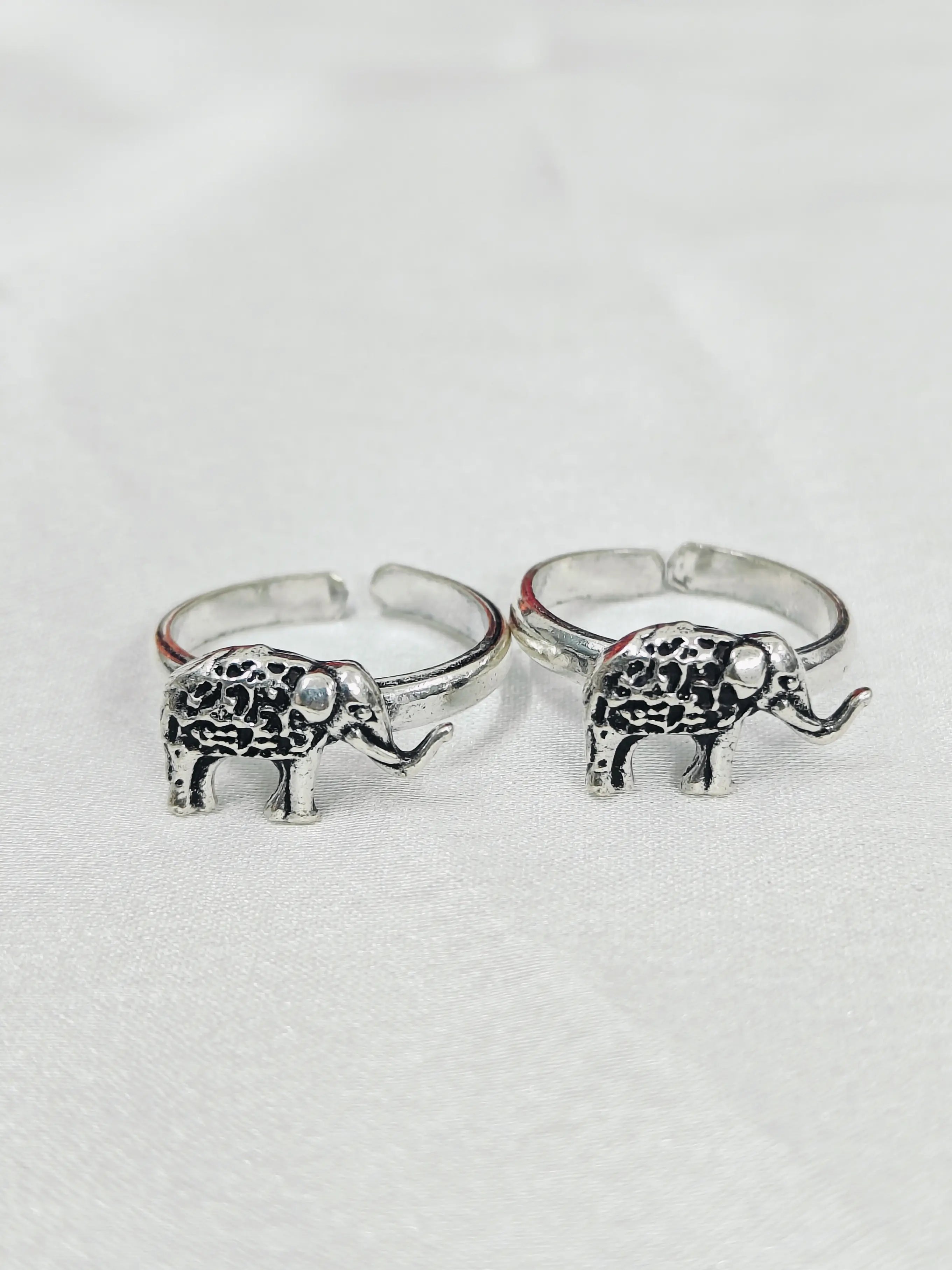 Two silver elephant-shaped rings on a light gray background