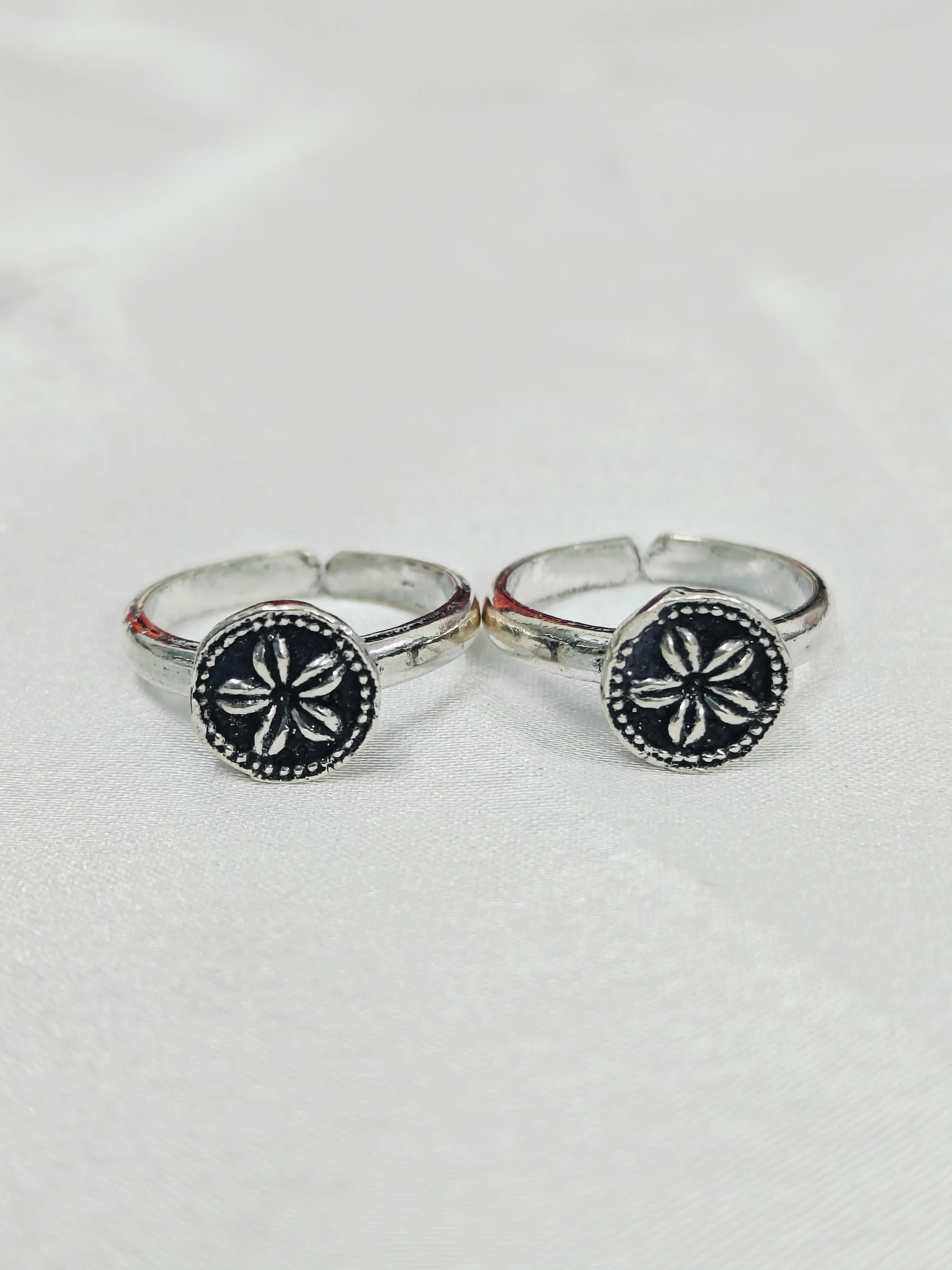 Two silver rings with black circular designs on a white background