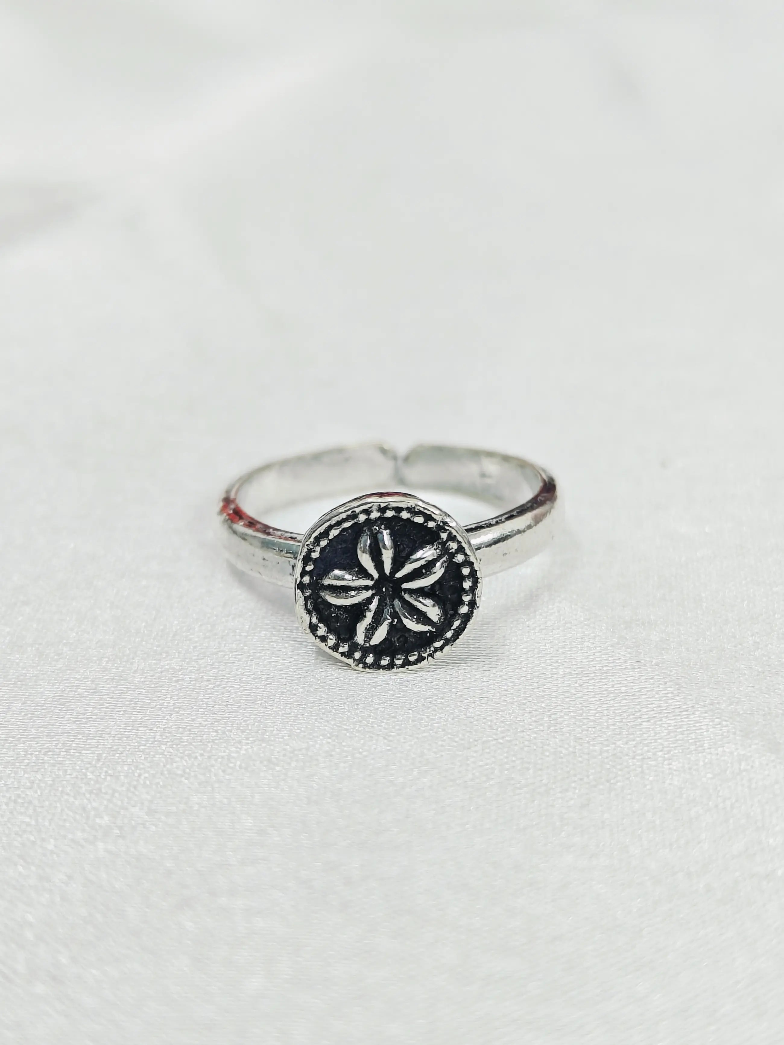 Silver ring with a black circular design on a white background