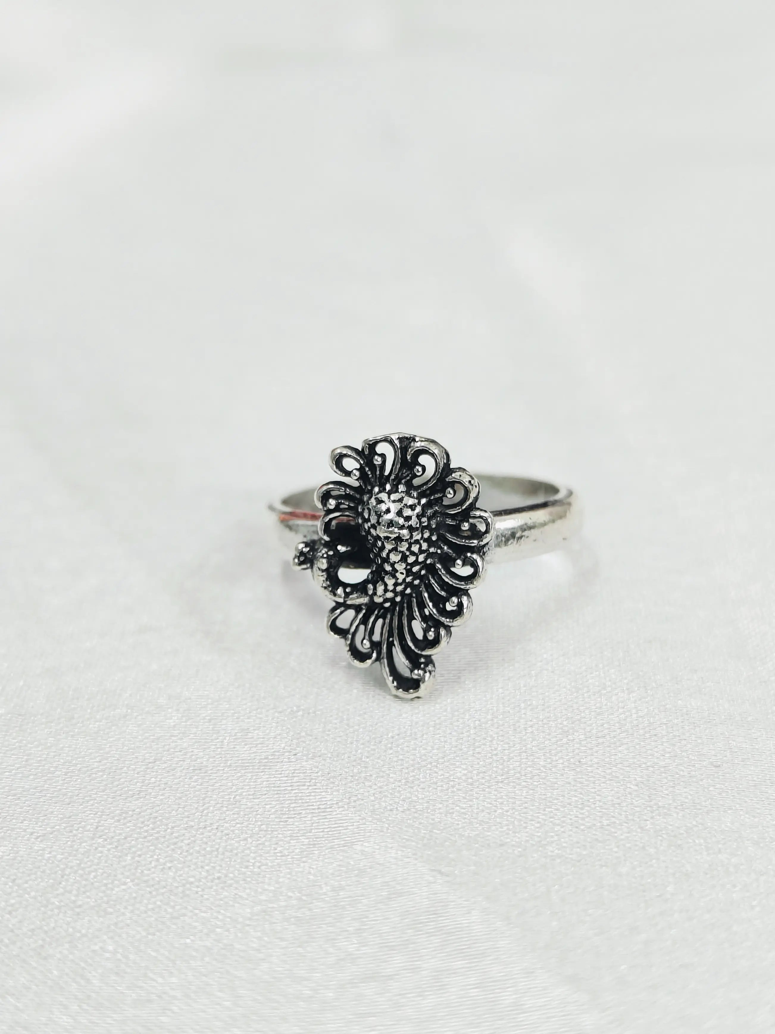Silver ring with intricate black design on a white background