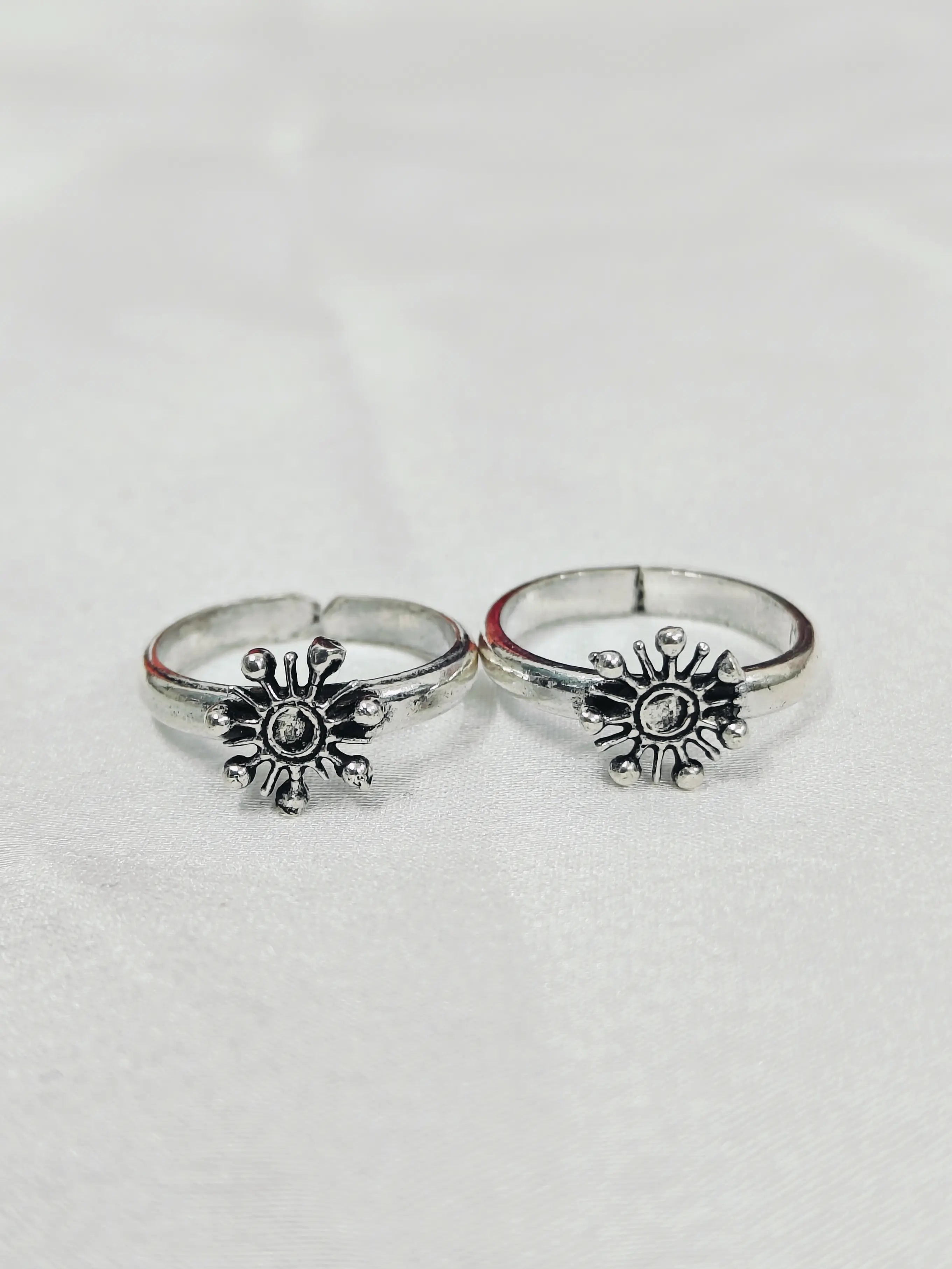 Two silver rings with sunflower designs on a light gray background