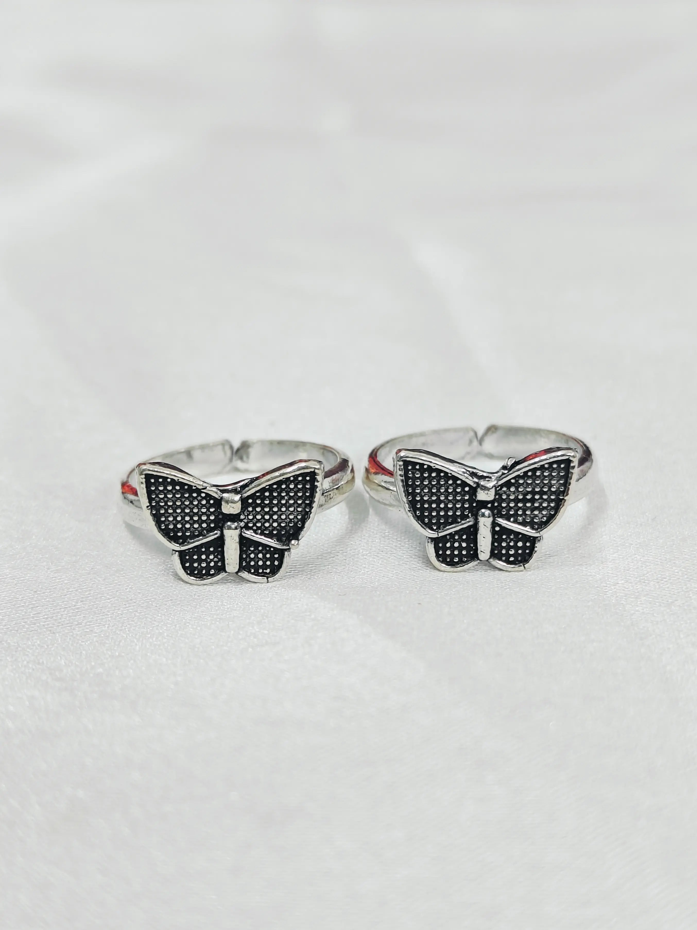 Butterfly-shaped silver rings with black gemstones on a white background