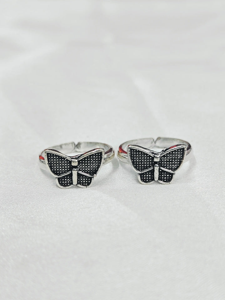 Butterfly-shaped silver rings with black gemstones on a white background
