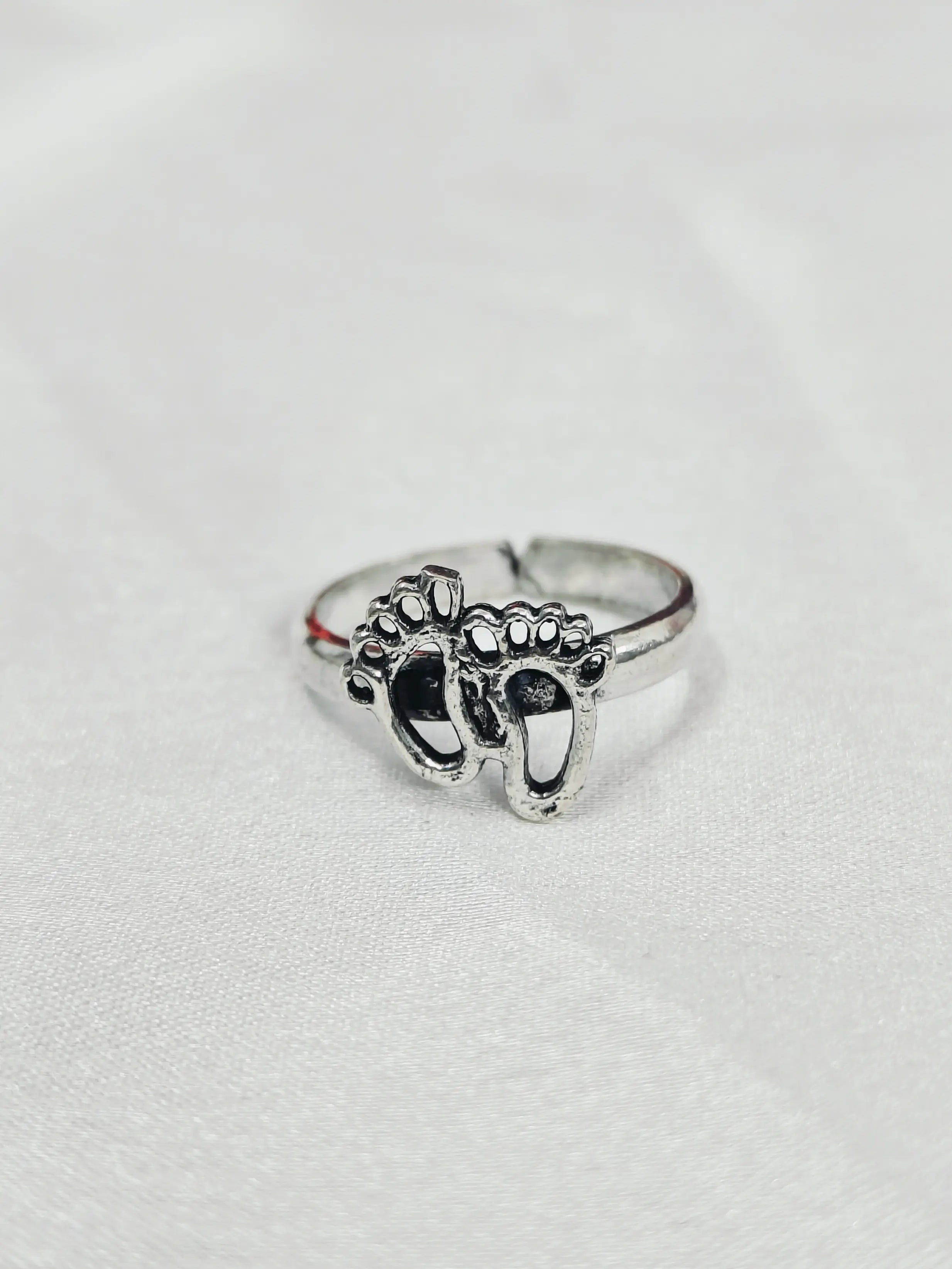 Silver ring with paw print design on a light gray background