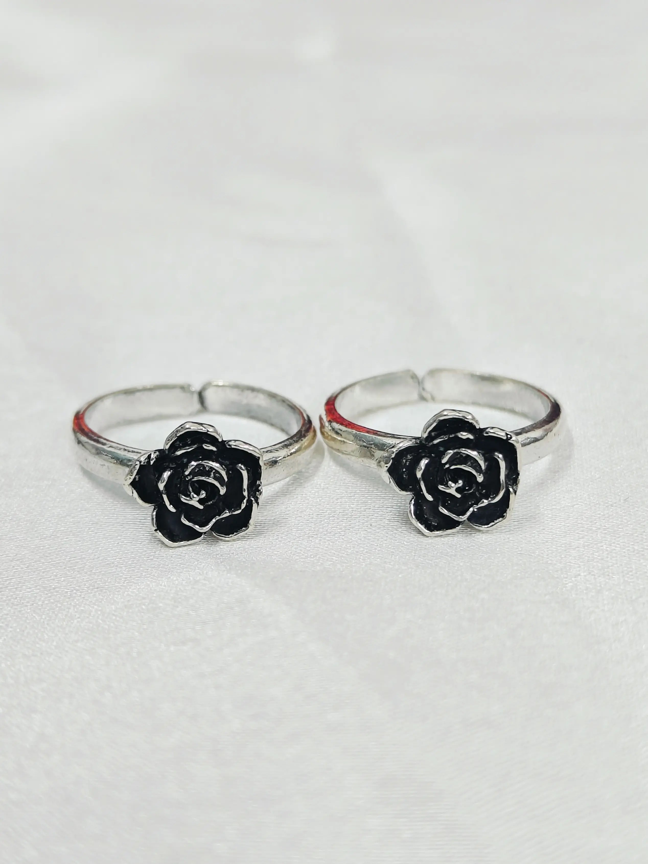 Two silver rings with black rose designs on a white background