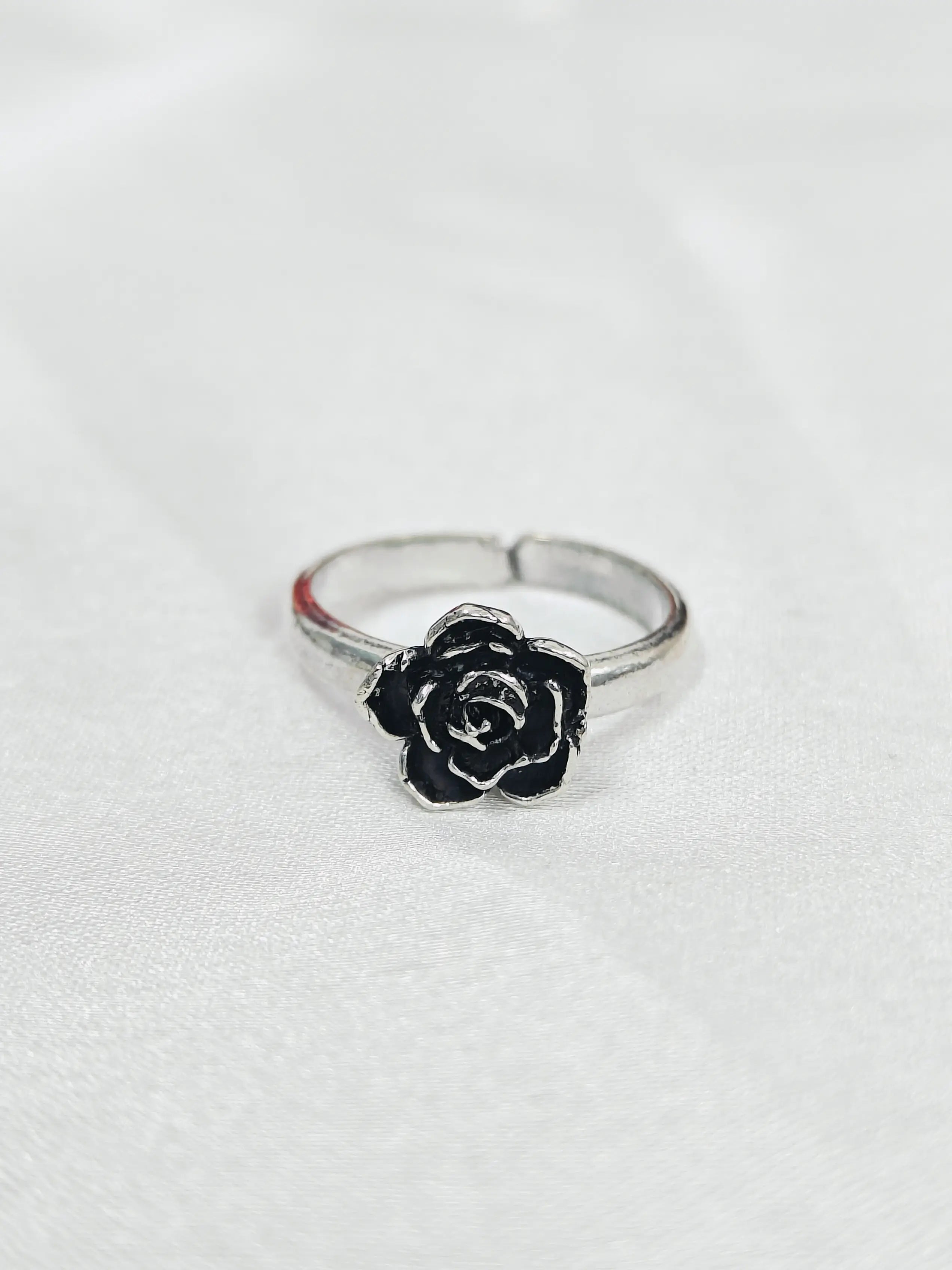 Silver ring with a black rose design on a white background