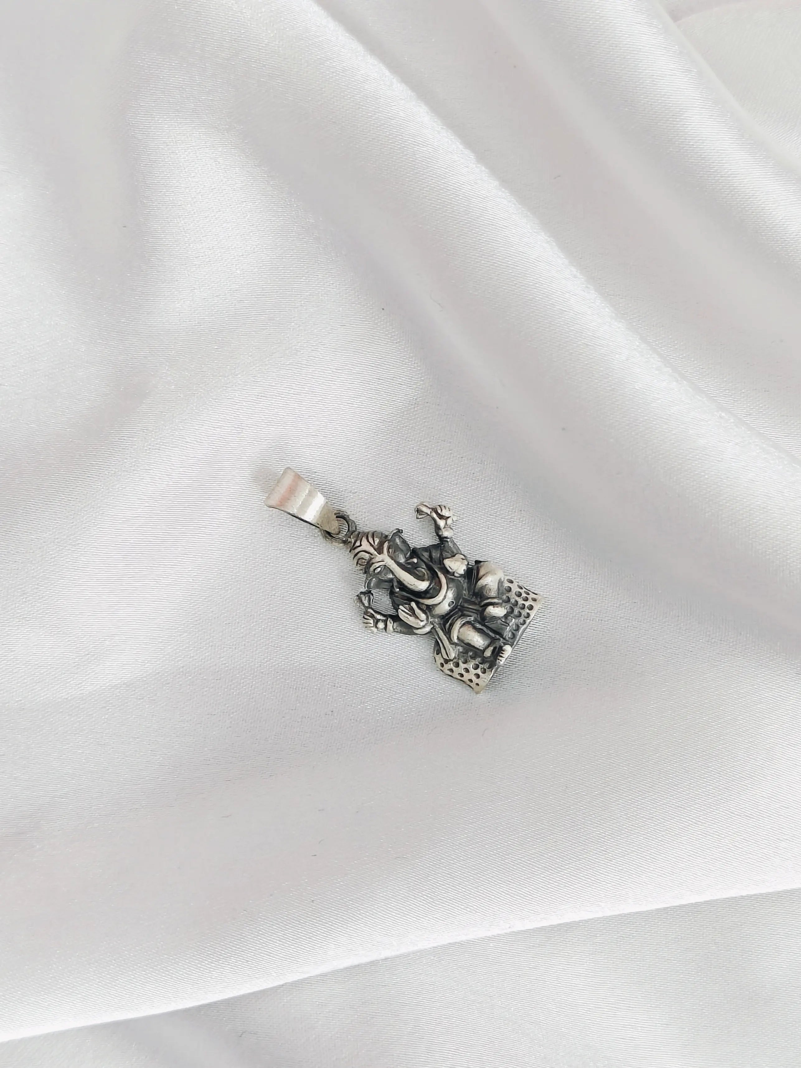 Silver pendant on a white fabric background