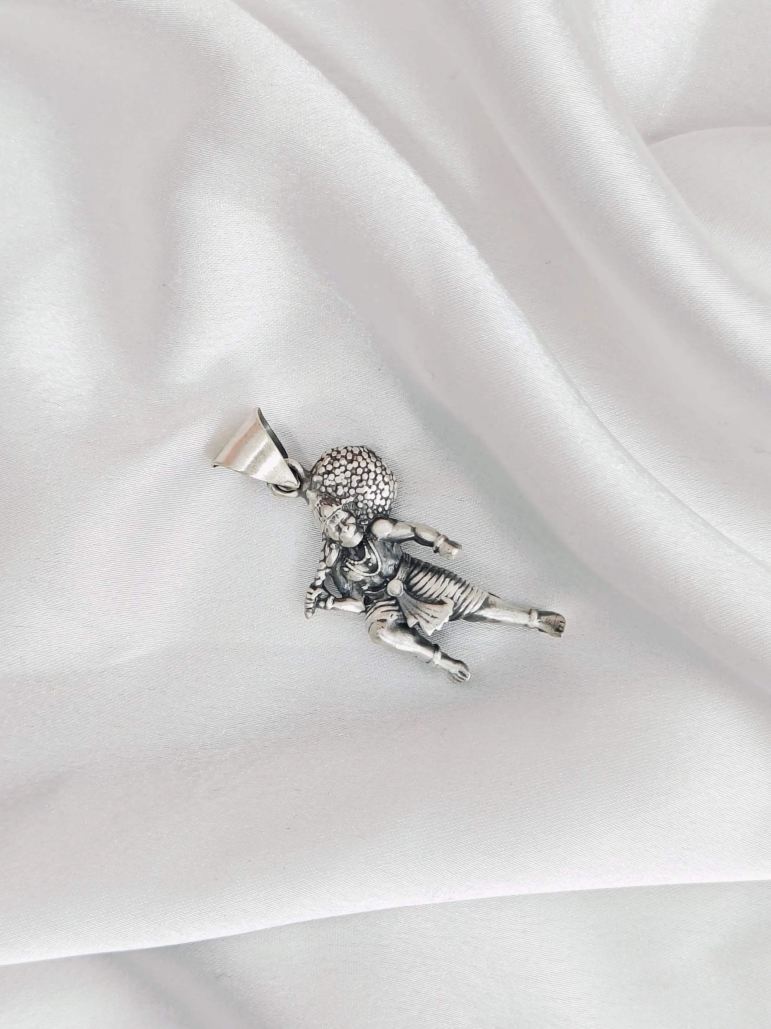 Silver pendant of a child on a white satin background