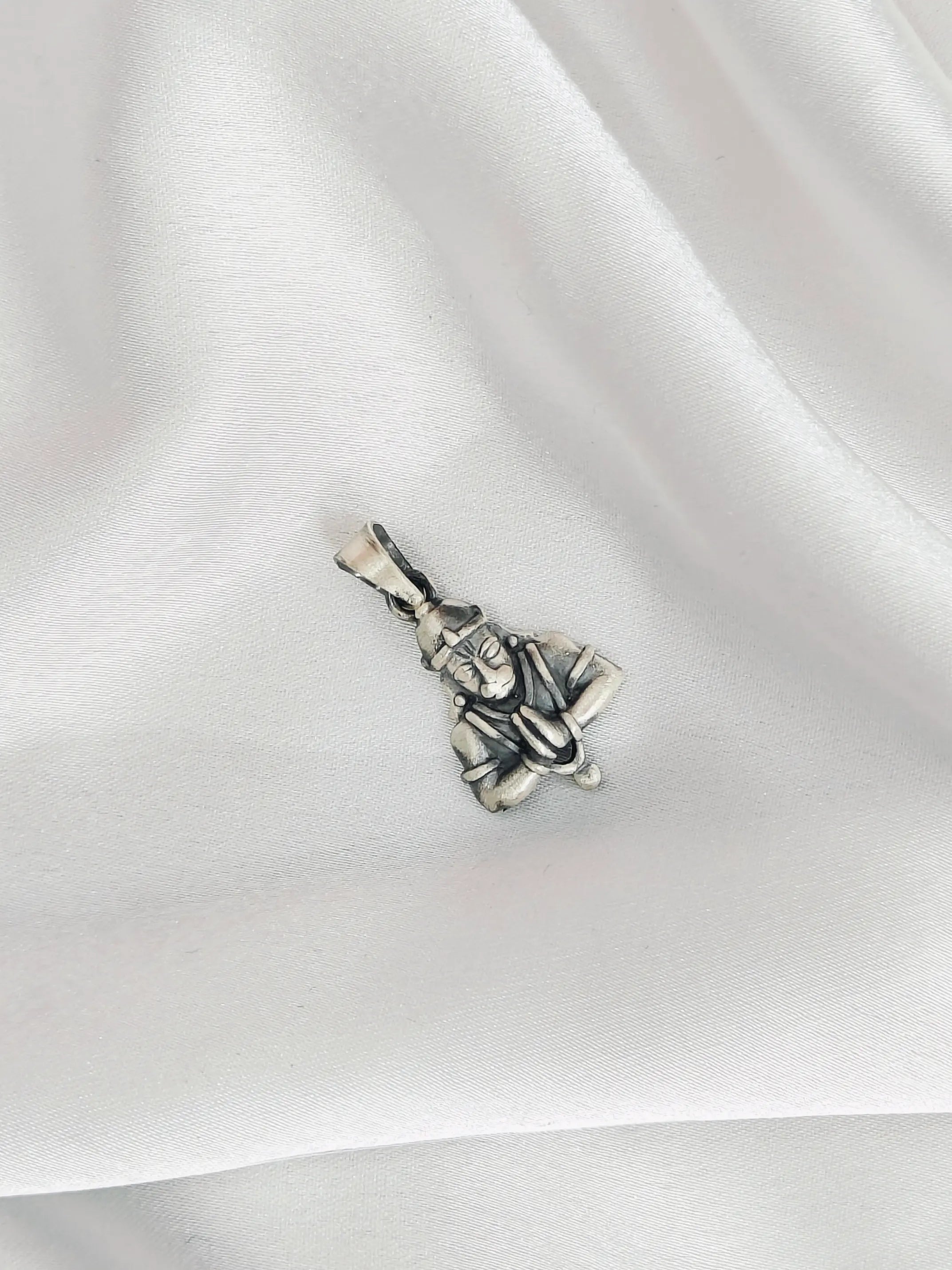 Silver pendant of a person on a white fabric background