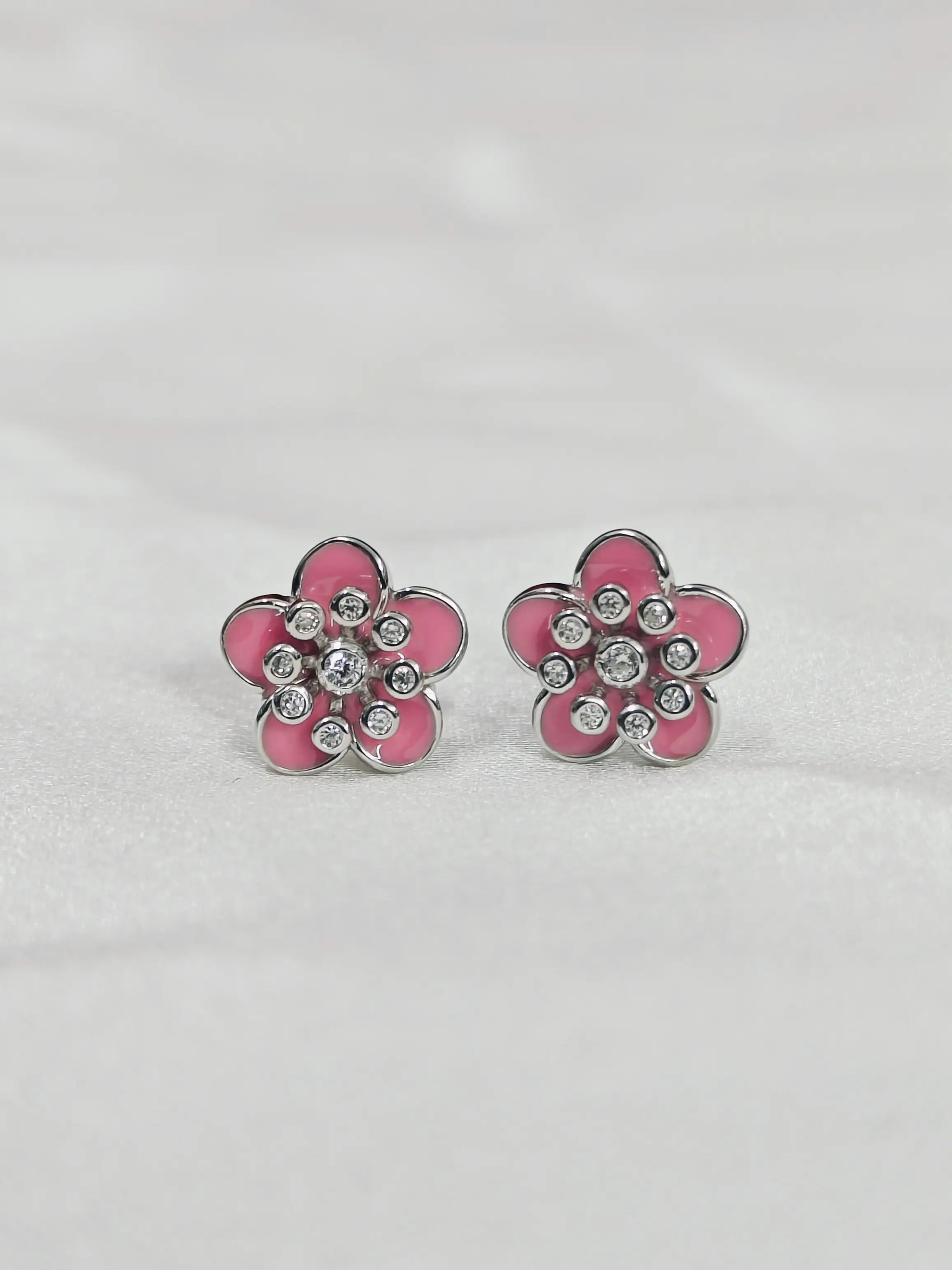 Pink flower-shaped earrings with clear stones on a light gray background
