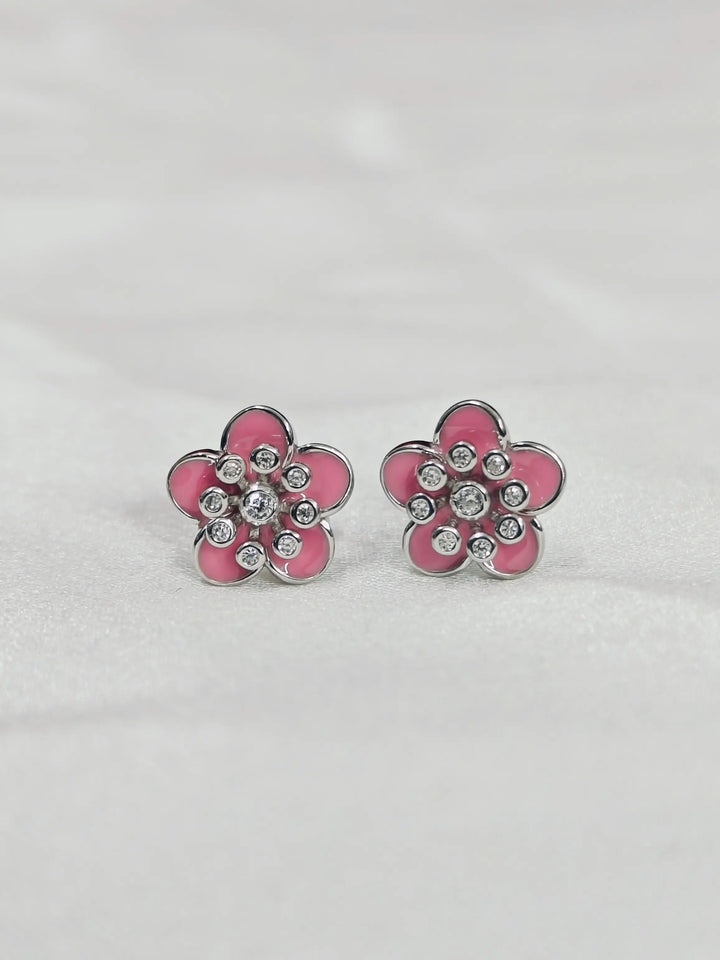 Pink flower-shaped earrings with clear stones on a light gray background