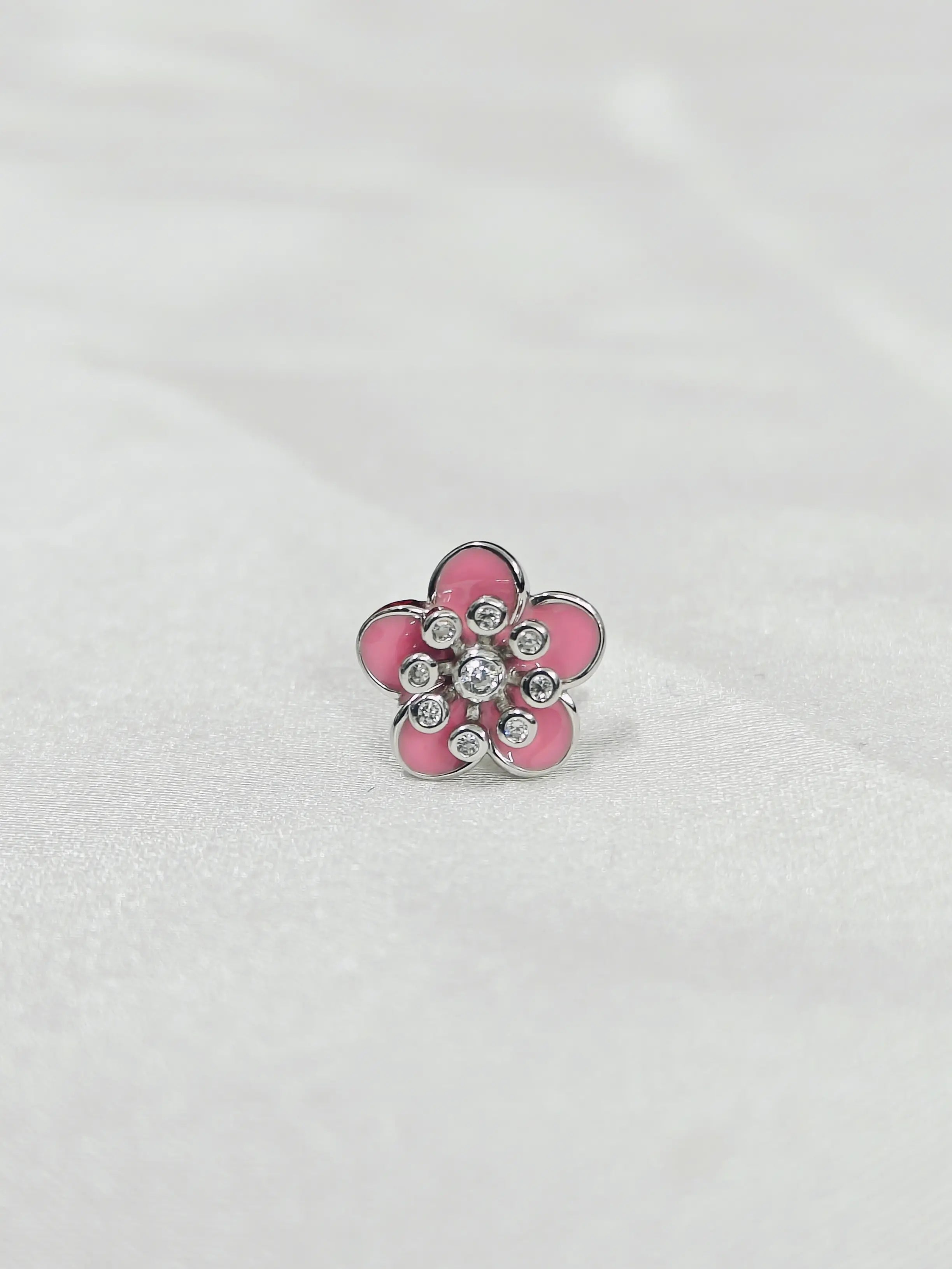 Pink flower-shaped object with embedded crystals on a white background
