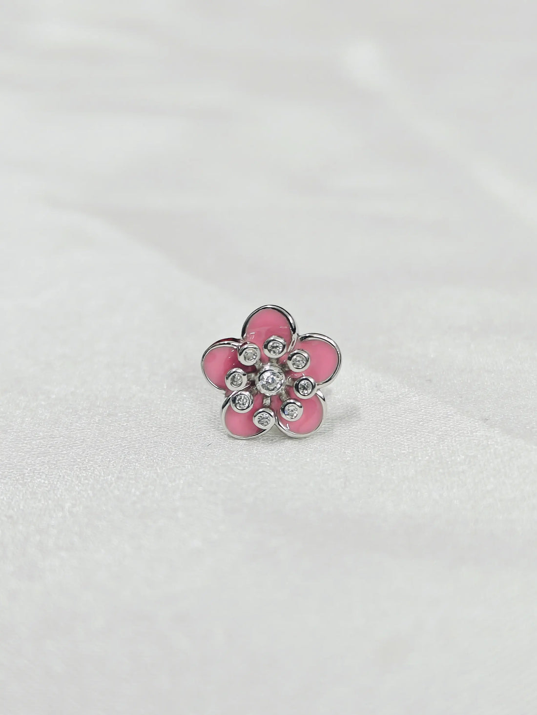Pink flower-shaped object with embedded crystals on a white background