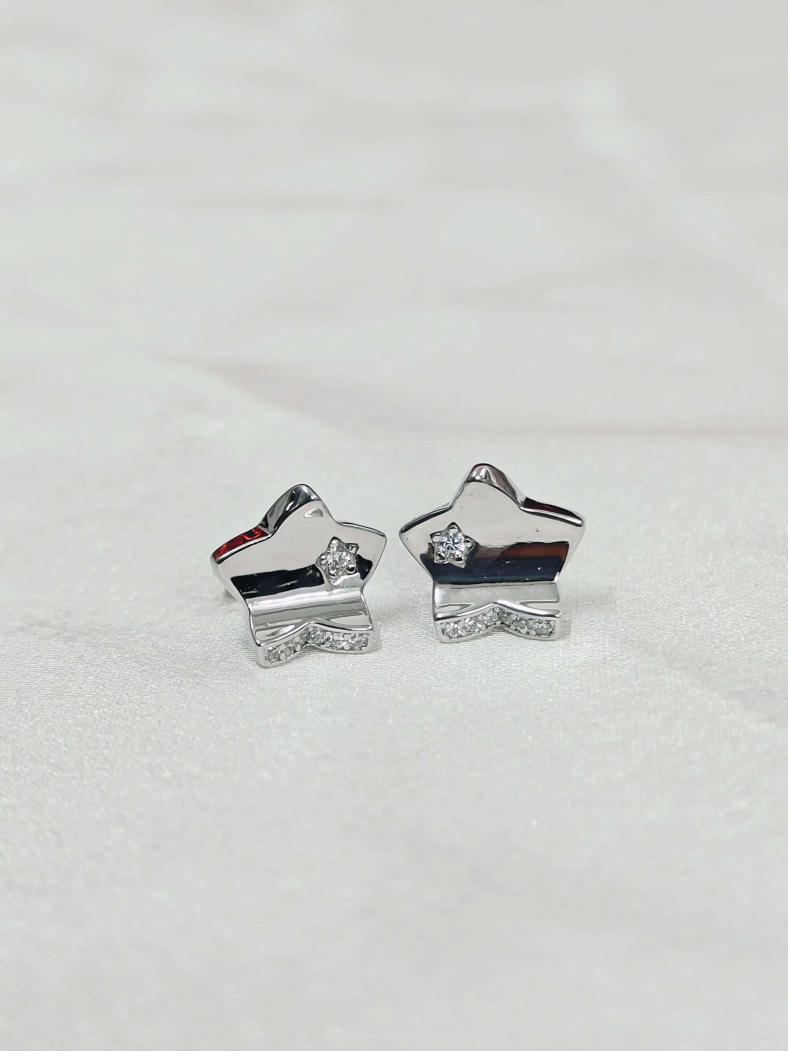 Silver star-shaped earrings on a light gray background