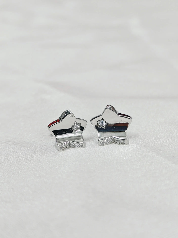 Silver star-shaped earrings on a light gray background