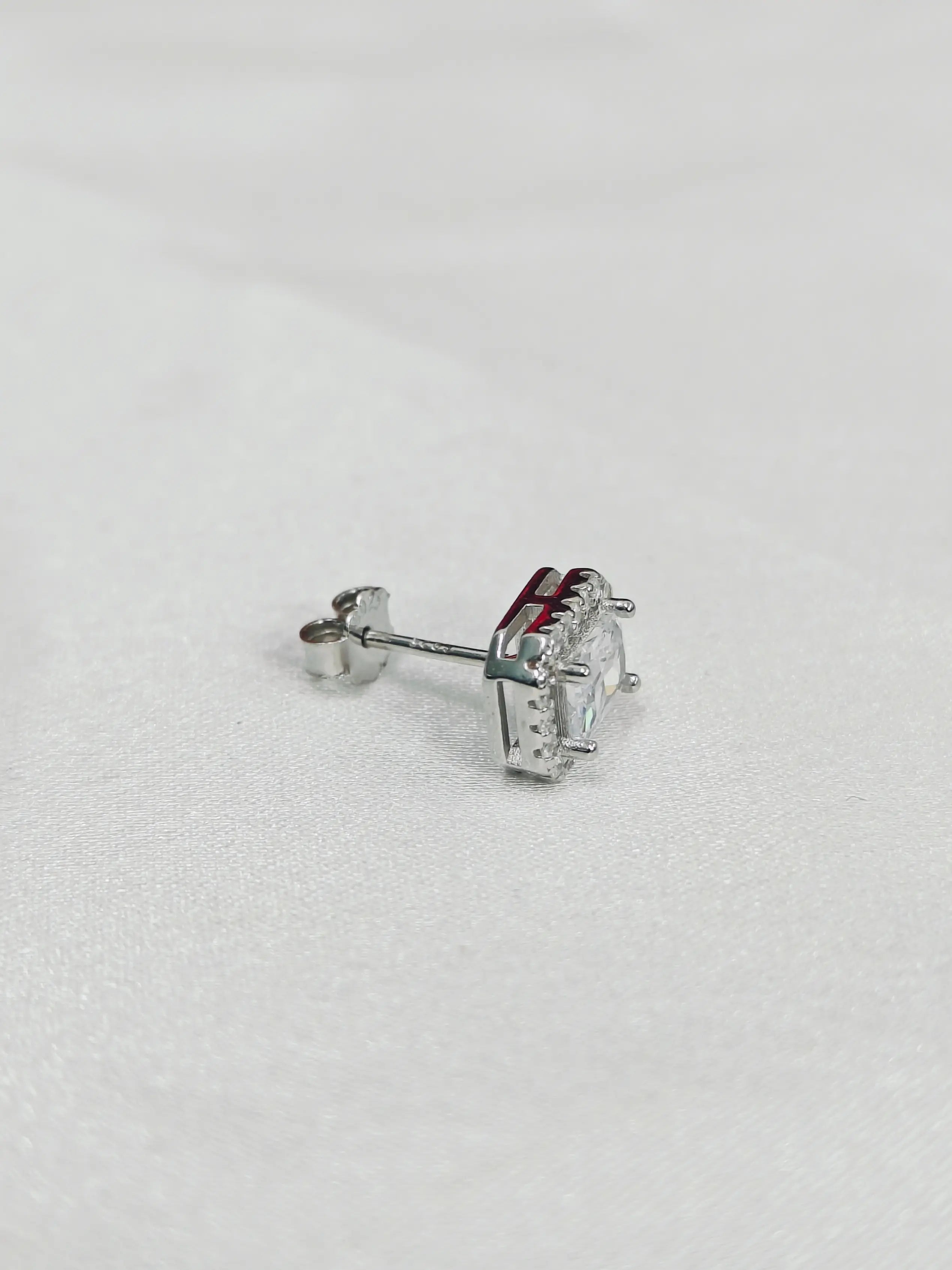 Silver earring with a clear gemstone on a light gray background