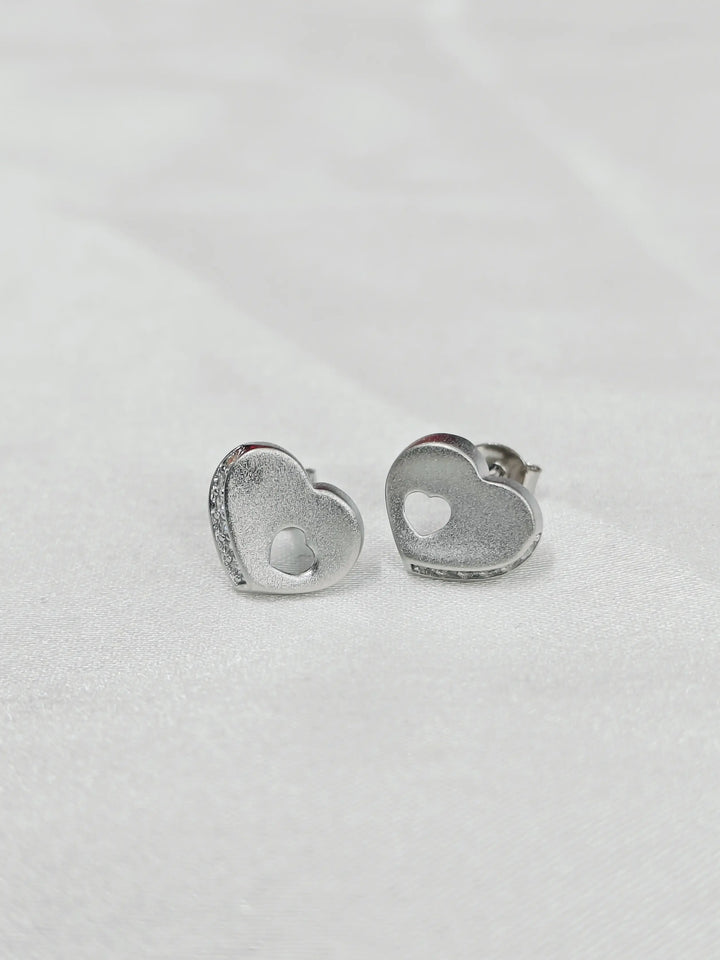 Heart-shaped silver earrings on a light gray background