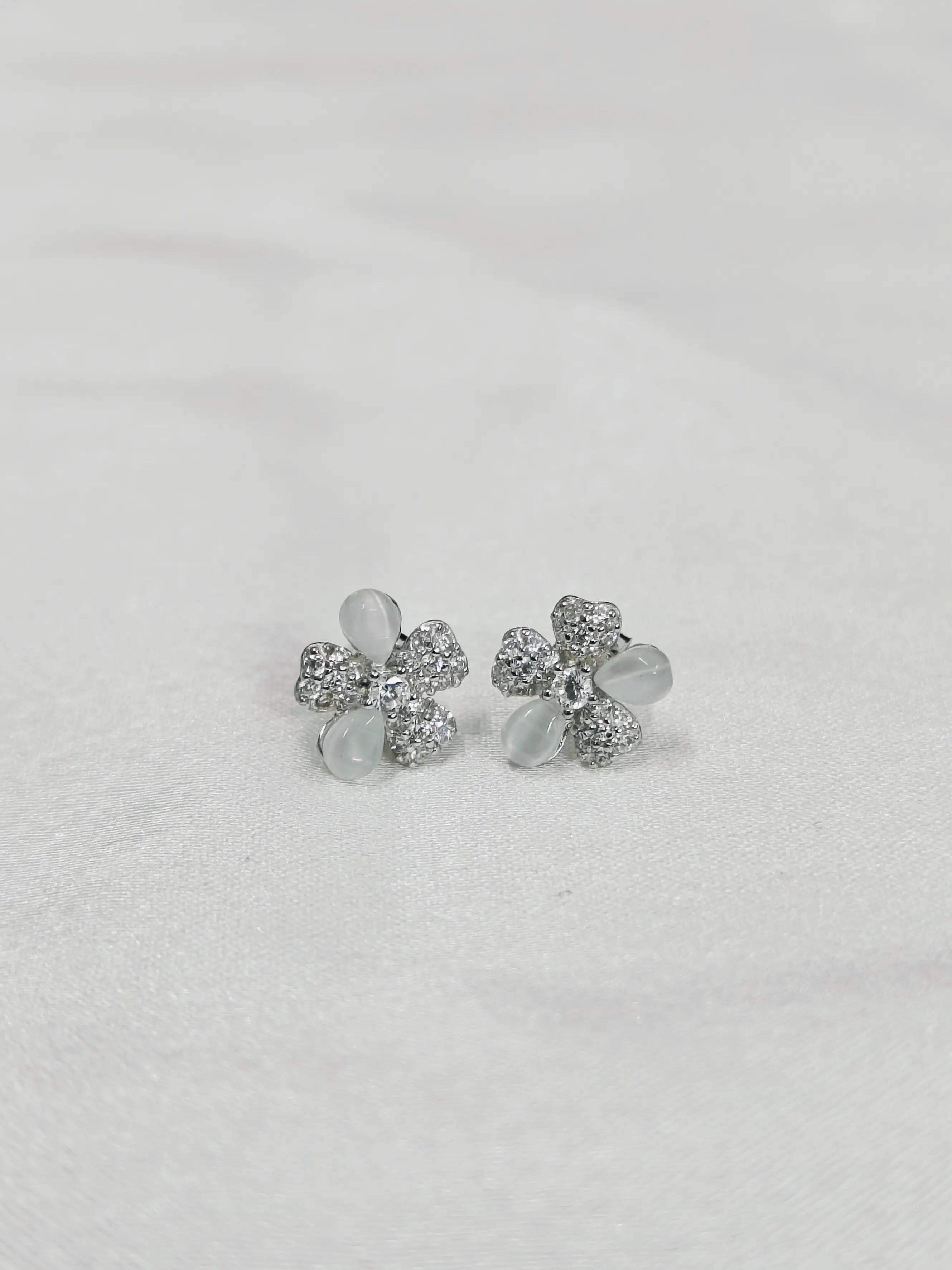 Silver flower-shaped earrings on a light gray background