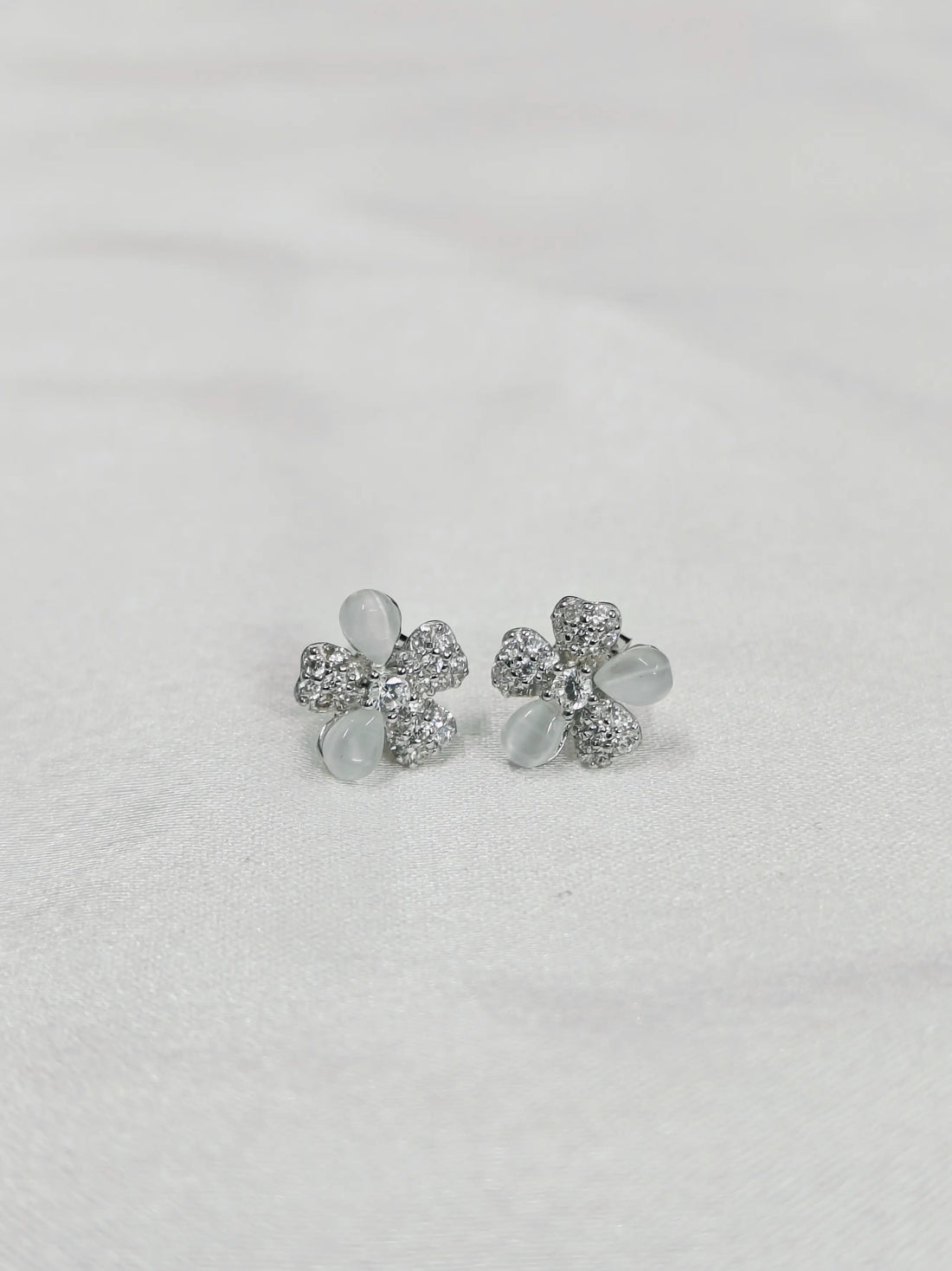 Silver flower-shaped earrings on a light gray background
