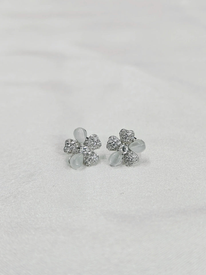Silver flower-shaped earrings on a light gray background
